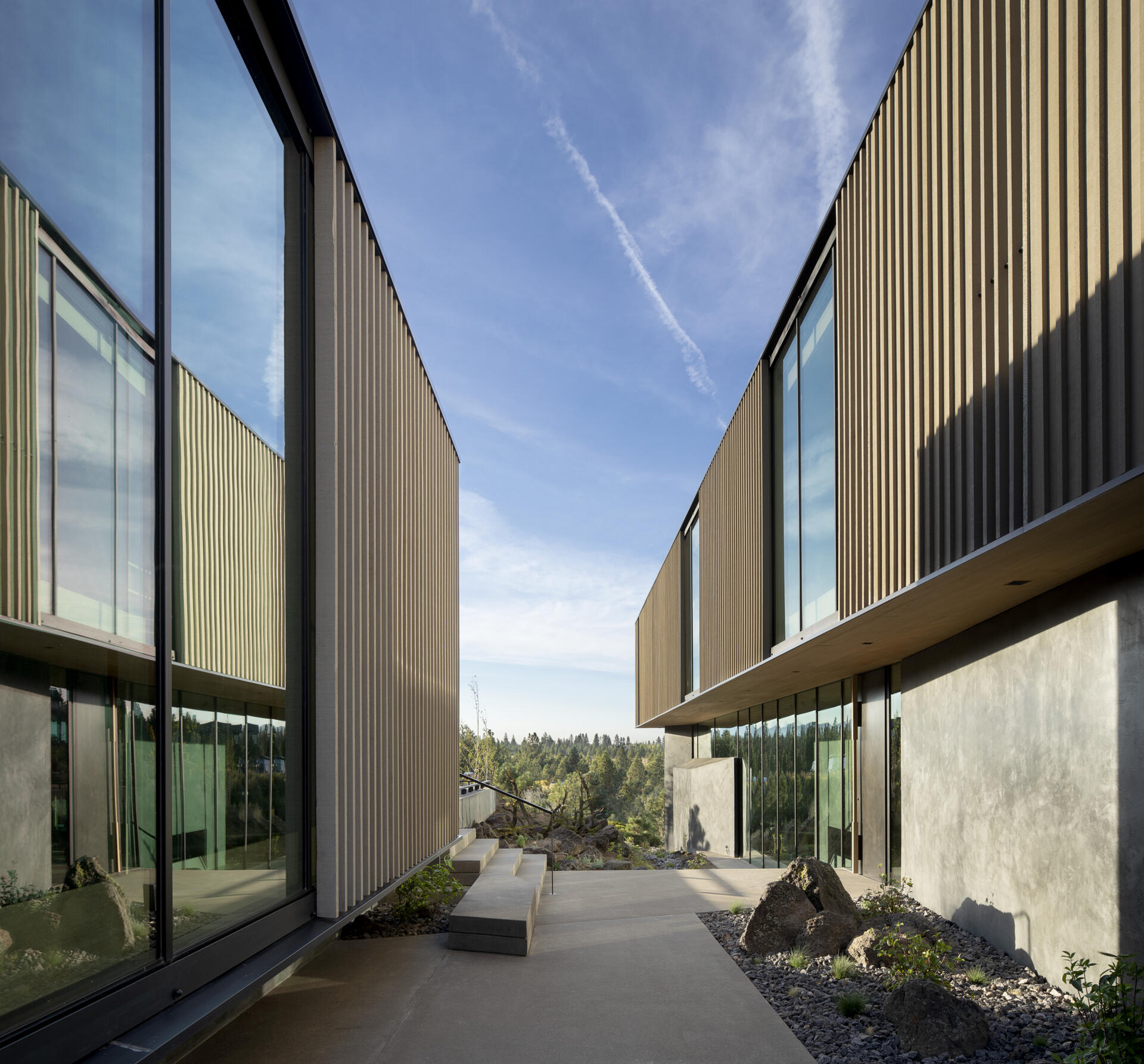 This modern home is designed as a series of cascading platforms that step down a pumice-covered hillside. Inspired by nearby volcanic rock formations, faceted mass walls anchor the structure, guiding movement and framing both intimate and expansive views. 