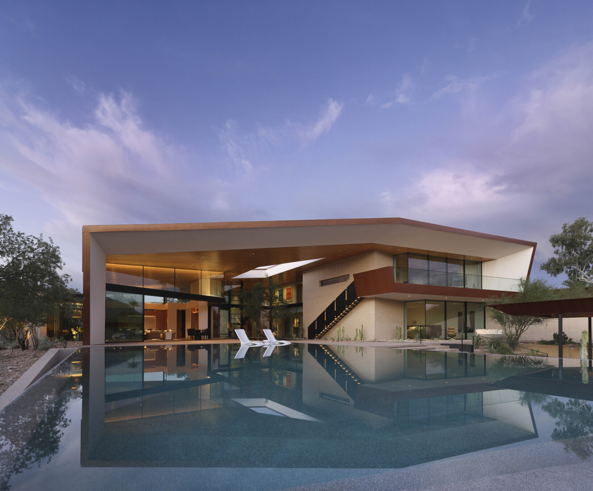 The infinity-edge pool cascades gently, its reflective surface mirroring the sky by day and glowing with sunset colors in the evening. This water feature also plays a role in passive cooling, enhancing comfort in the desert heat.