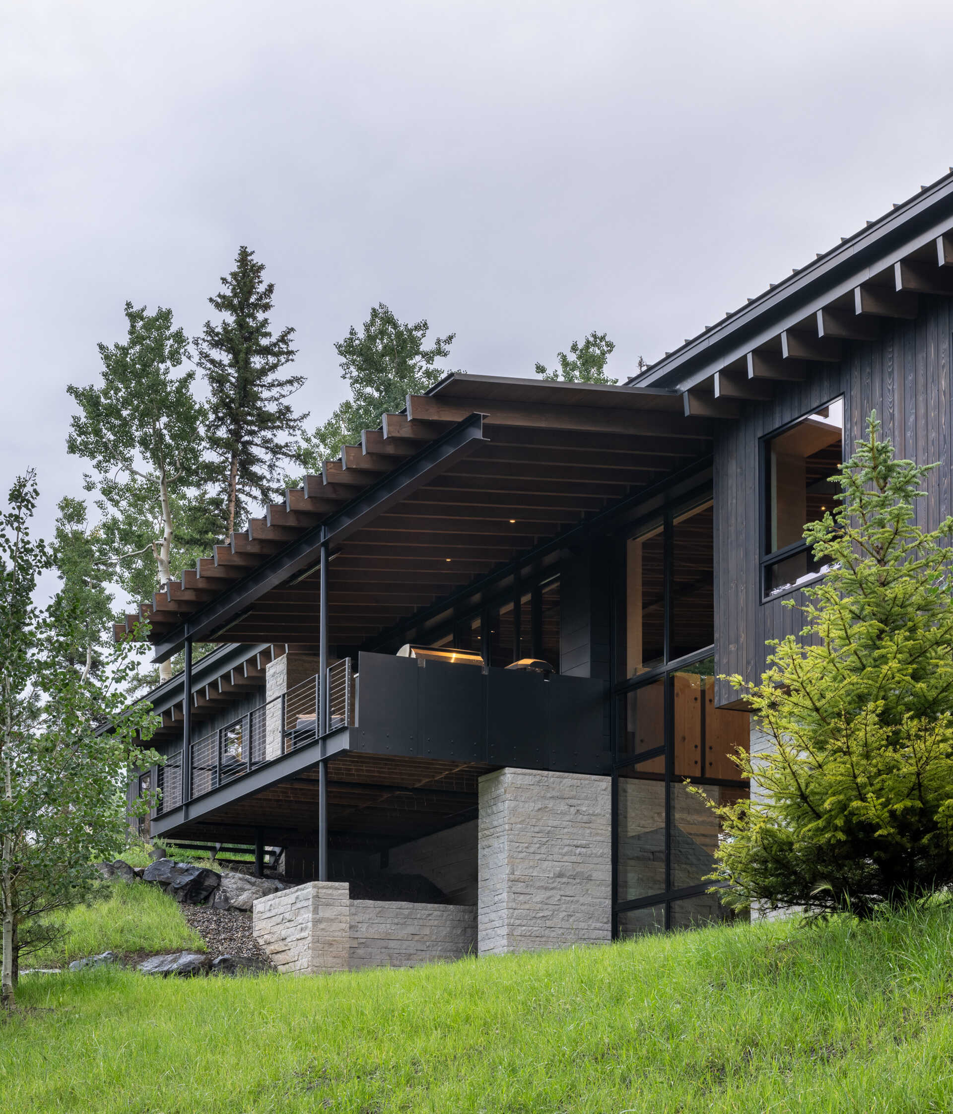 Rough sawn cedar, limestone, and steel ground this modern home in its wooded setting.