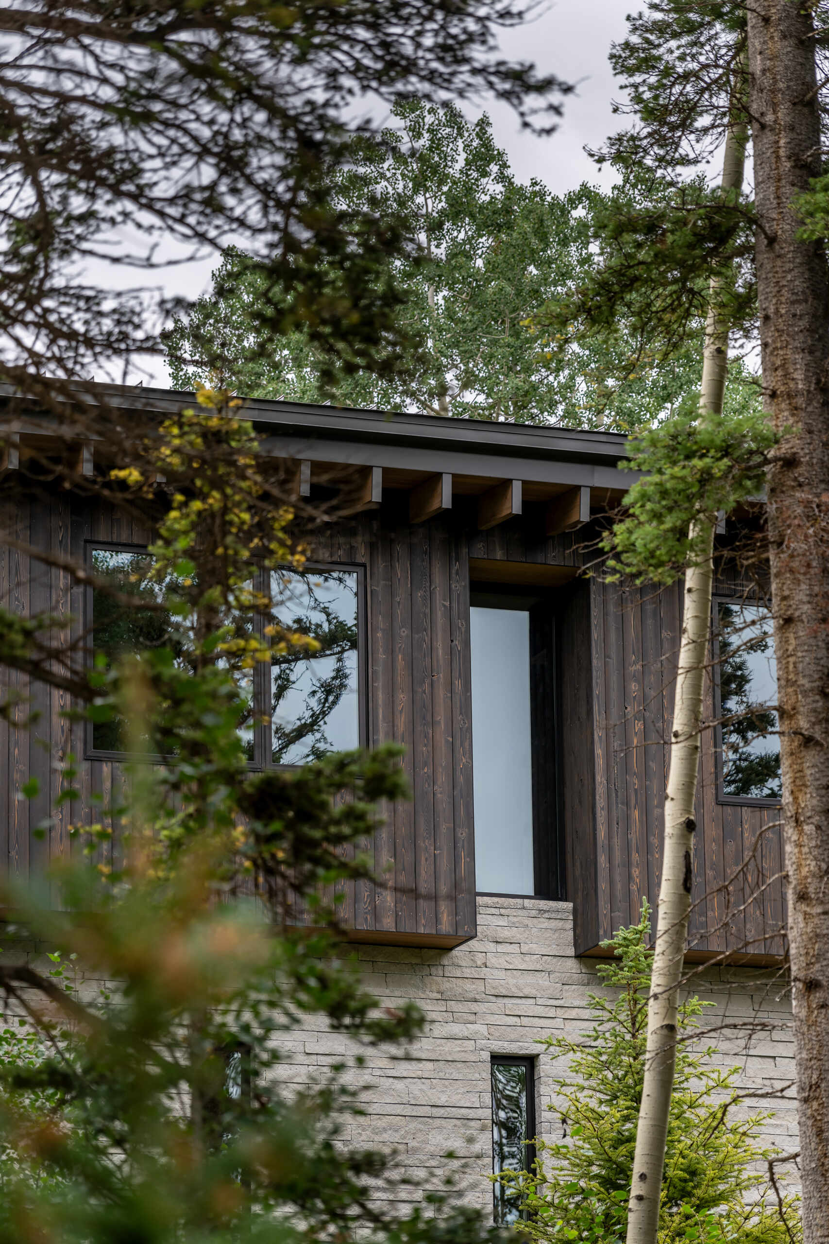 Rough sawn cedar, limestone, and steel ground this modern home in its wooded setting.