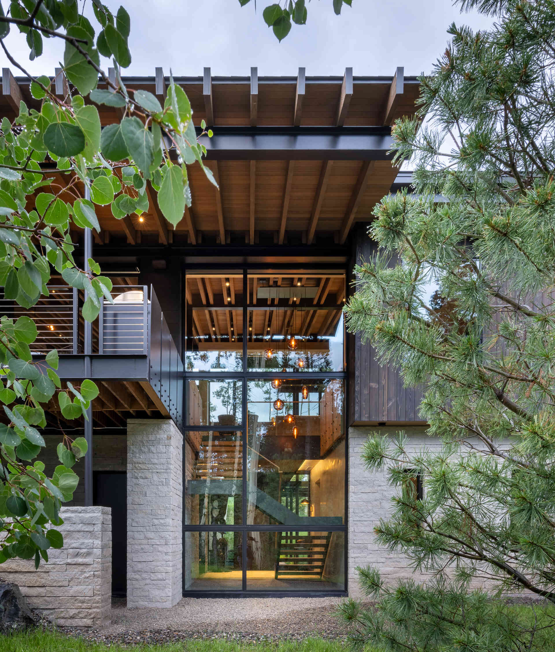 Floor-to-ceiling glass reveals forest views at nearly every turn, most dramatically at the entry, where a glass wall frames the woods as soon as you step inside.