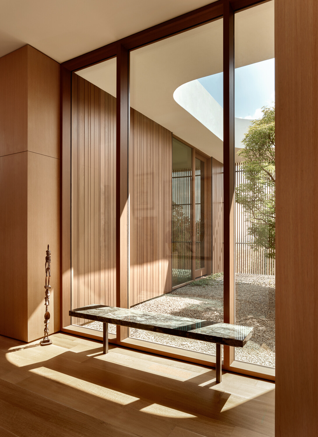 Mahogany-framed window walls anchor the design. Their warmth balances the rugged native stone and wood used throughout the home, while expansive glazing maximizes daylight and creates fluid connections with the outdoors.