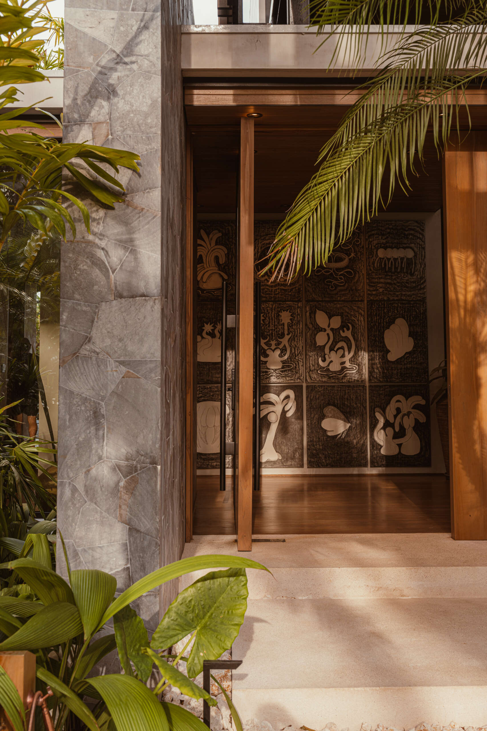 A modern oversized pivoting wood front door.