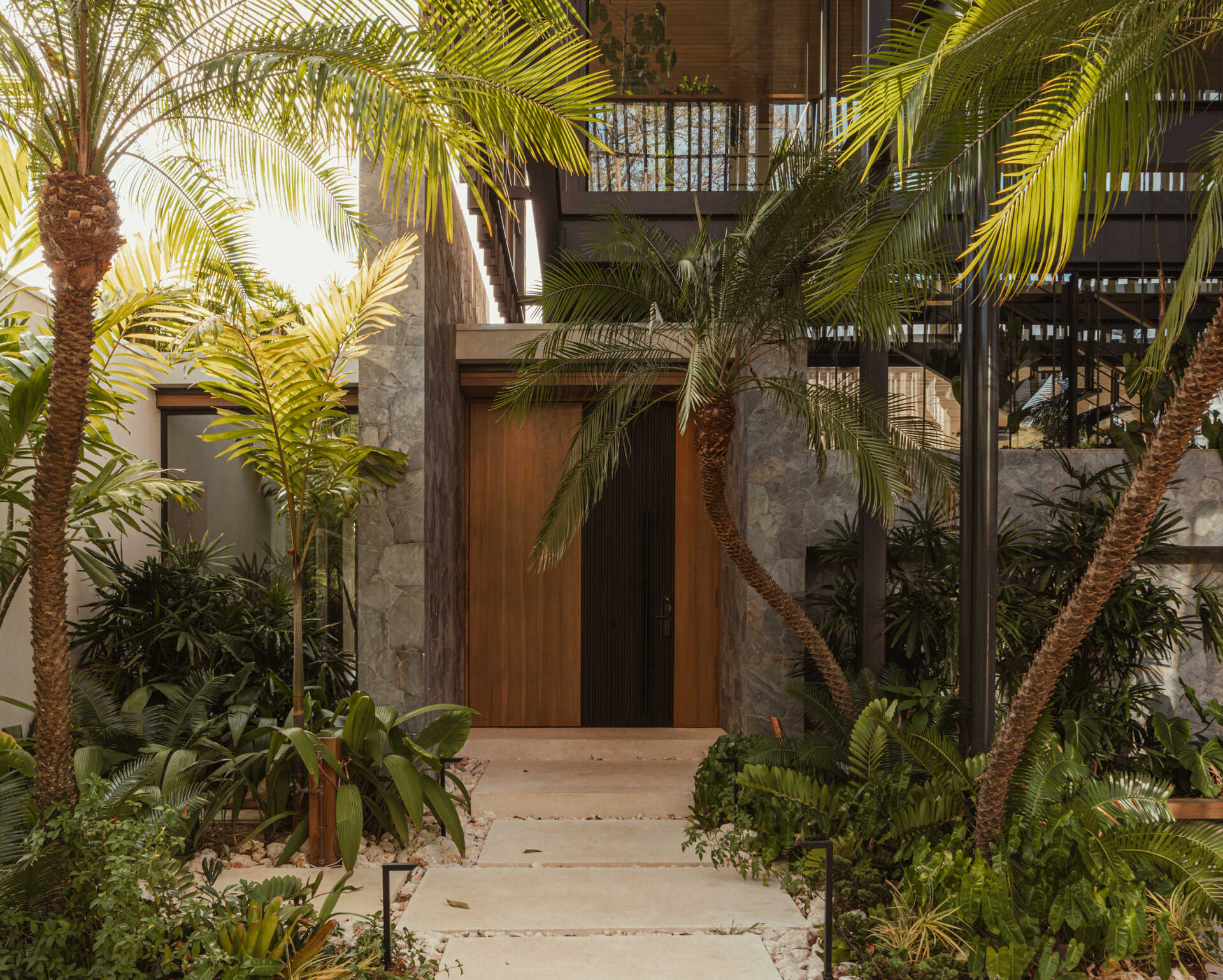 Arrival this modern home is through a lush stepping stone path where the home reveals itself slowly, framed by native plants and layered materials.