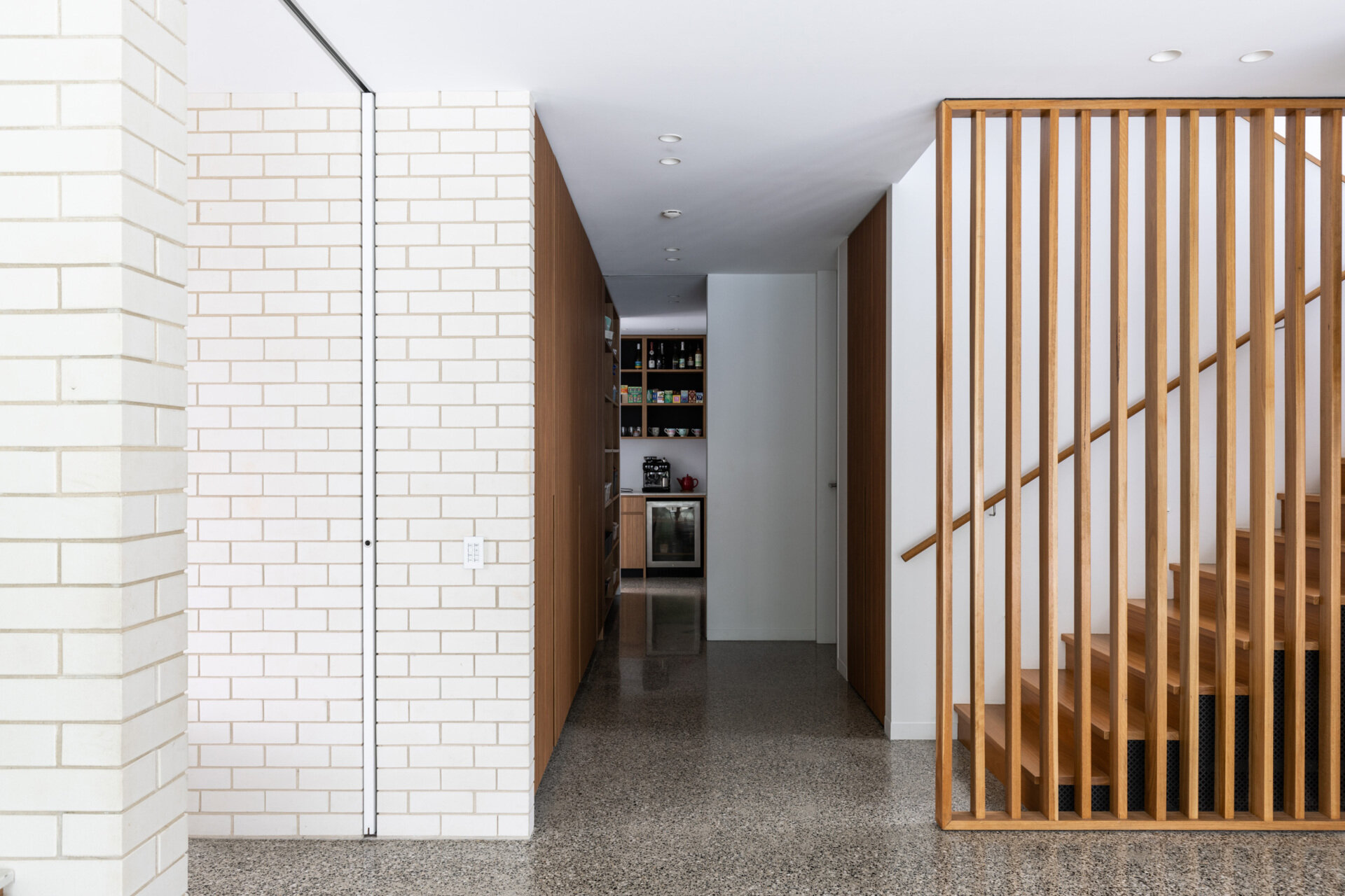 A central stair connects all levels, acting as a vertical spine through the home. Transitioning from the more open and transparent living spaces to the private upper floor, the stairs mark a shift in materiality and mood.