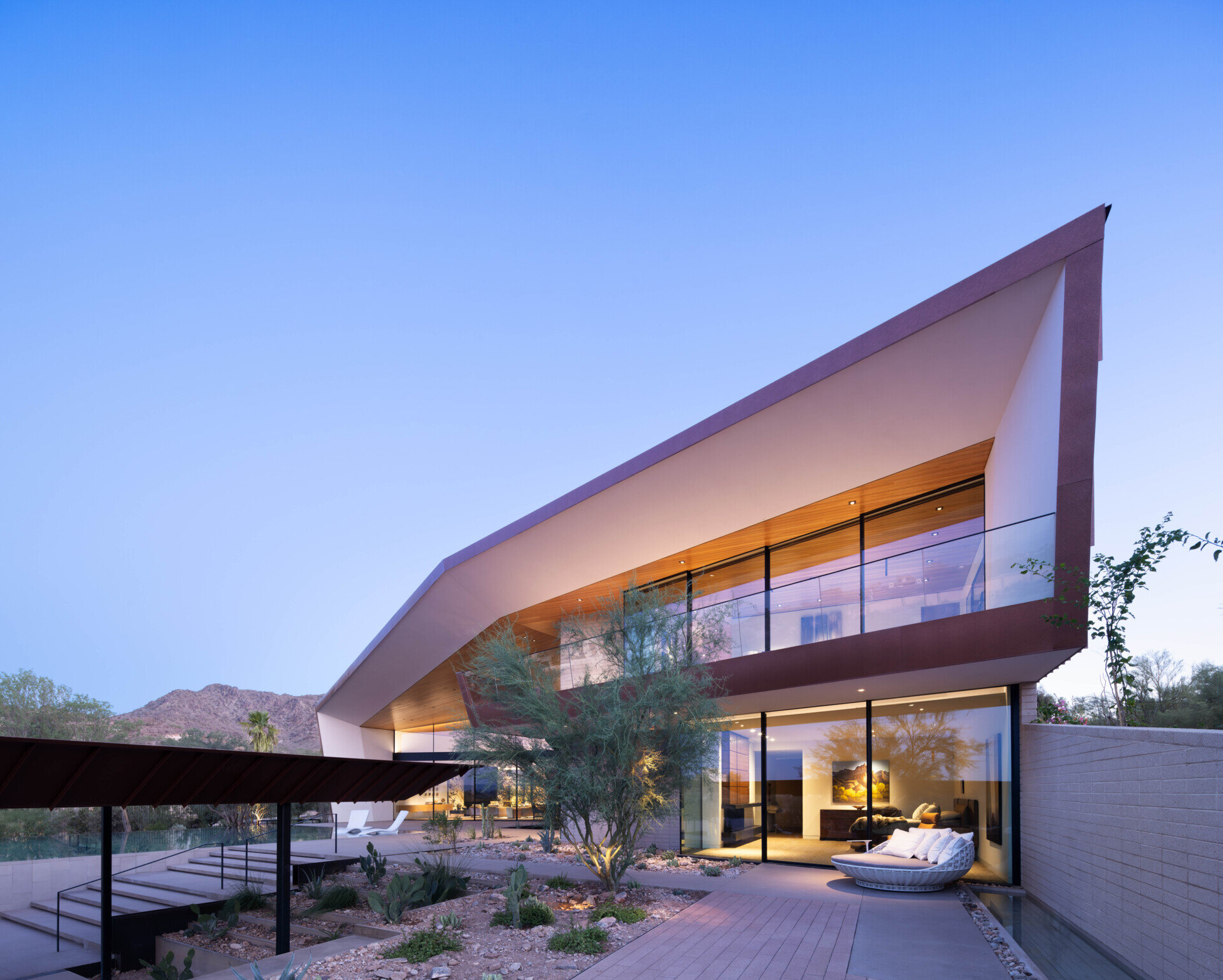 Terraces and balconies offer multiple vantage points to enjoy mountain and city views. A firepit creates a cozy evening gathering space, while an open-air cabana with a patterned metal trellis provides shade among dense vegetation.