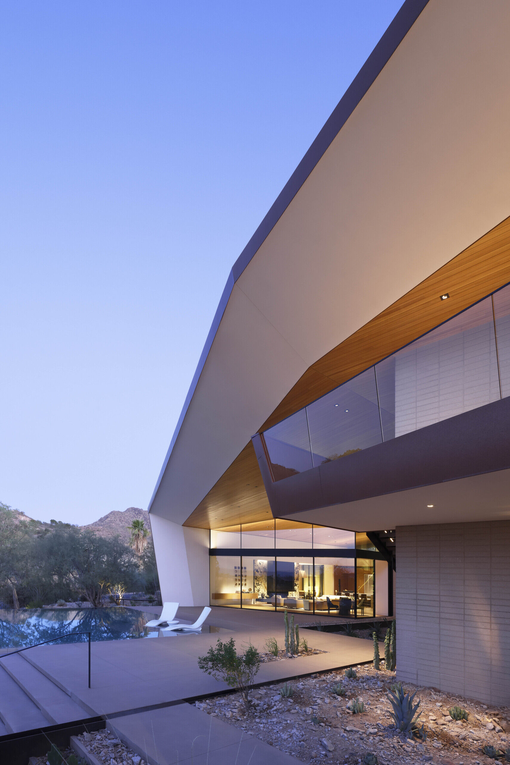 Terraces and balconies offer multiple vantage points to enjoy mountain and city views. A firepit creates a cozy evening gathering space, while an open-air cabana with a patterned metal trellis provides shade among dense vegetation.
