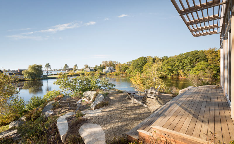 Wrapped in cedar and zinc that age to silver gray, the home blends seamlessly with its rocky setting beside the pond and ocean.