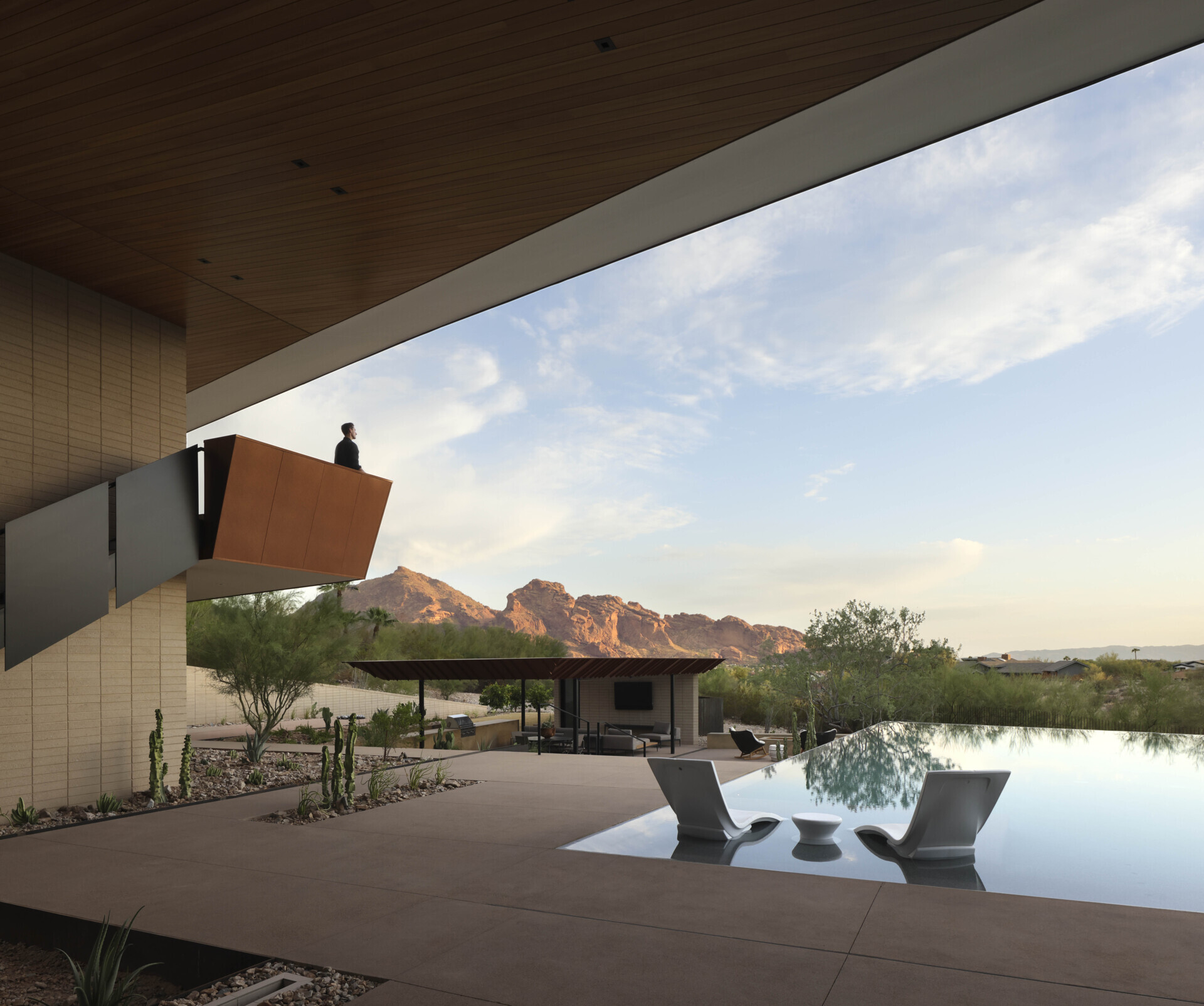 The infinity-edge pool cascades gently, its reflective surface mirroring the sky by day and glowing with sunset colors in the evening. This water feature also plays a role in passive cooling, enhancing comfort in the desert heat.