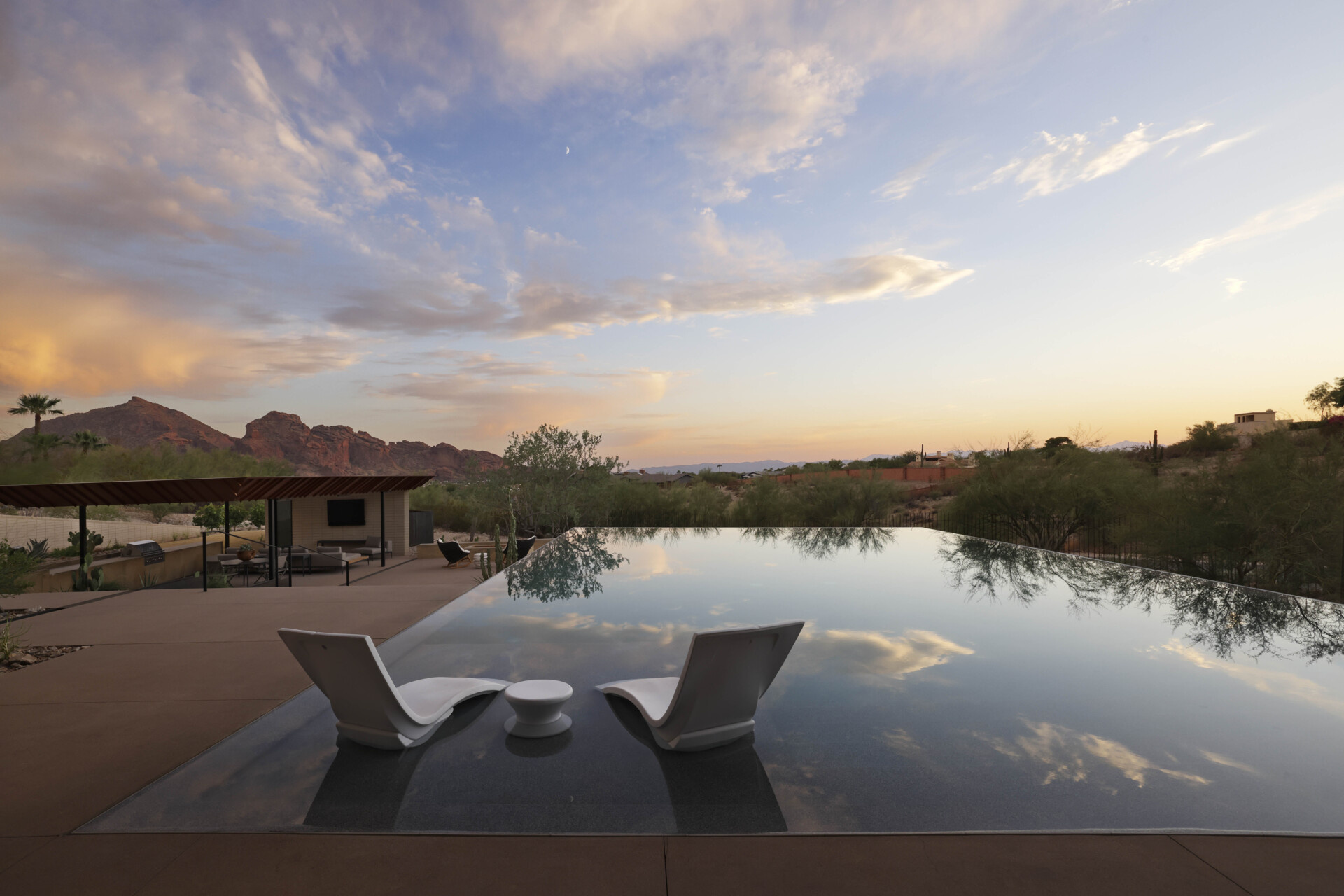 The infinity-edge pool cascades gently, its reflective surface mirroring the sky by day and glowing with sunset colors in the evening. This water feature also plays a role in passive cooling, enhancing comfort in the desert heat.