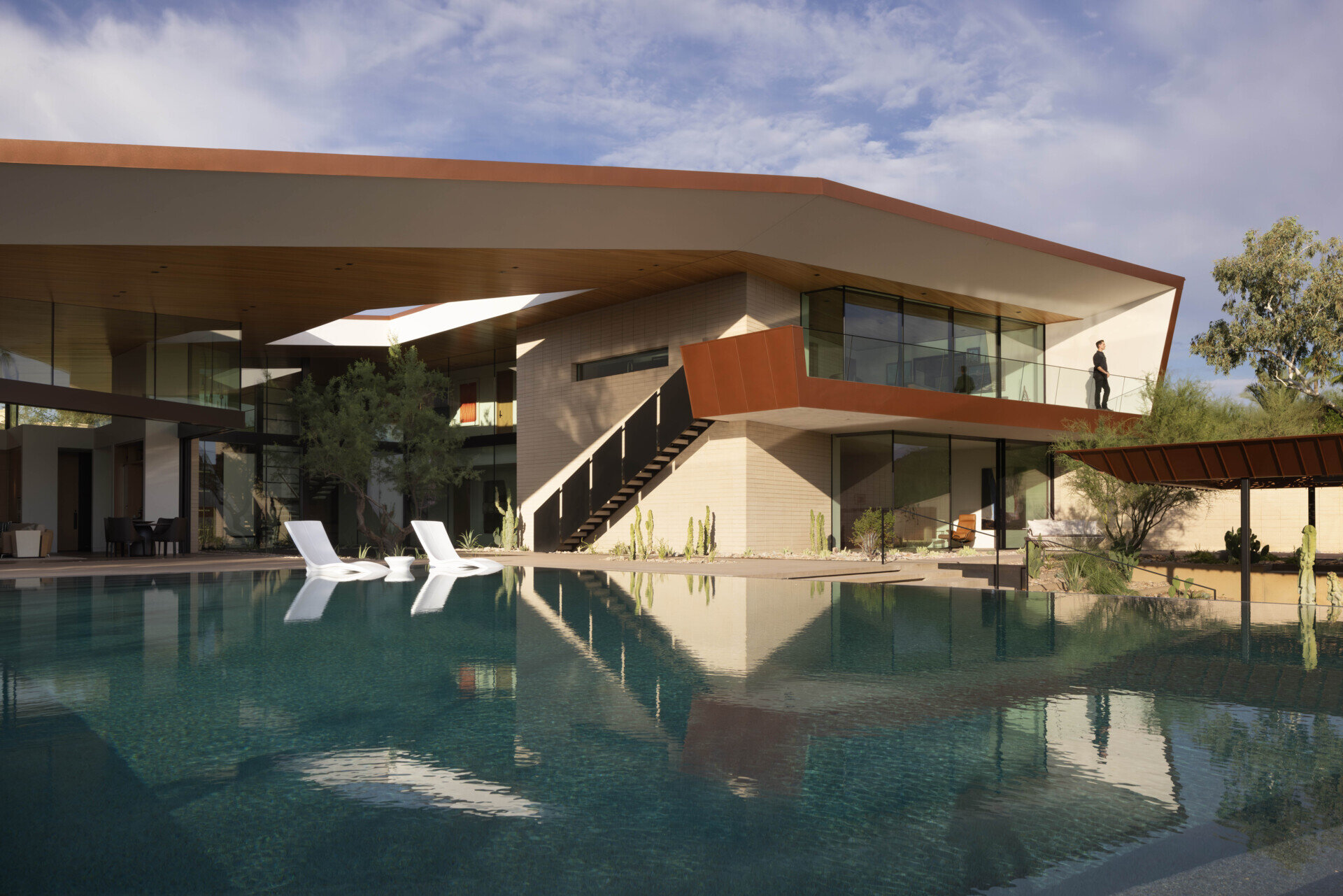 The infinity-edge pool cascades gently, its reflective surface mirroring the sky by day and glowing with sunset colors in the evening. This water feature also plays a role in passive cooling, enhancing comfort in the desert heat.