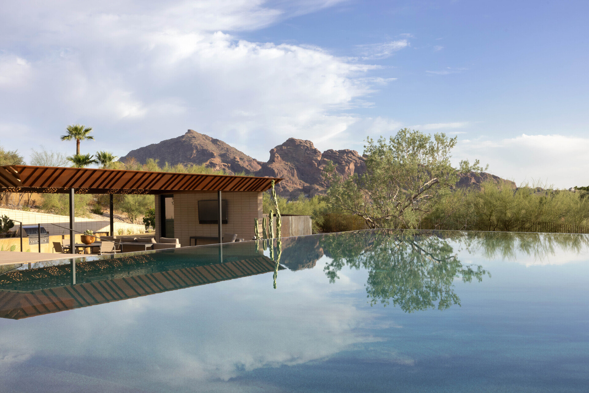 The infinity-edge pool cascades gently, its reflective surface mirroring the sky by day and glowing with sunset colors in the evening. This water feature also plays a role in passive cooling, enhancing comfort in the desert heat.