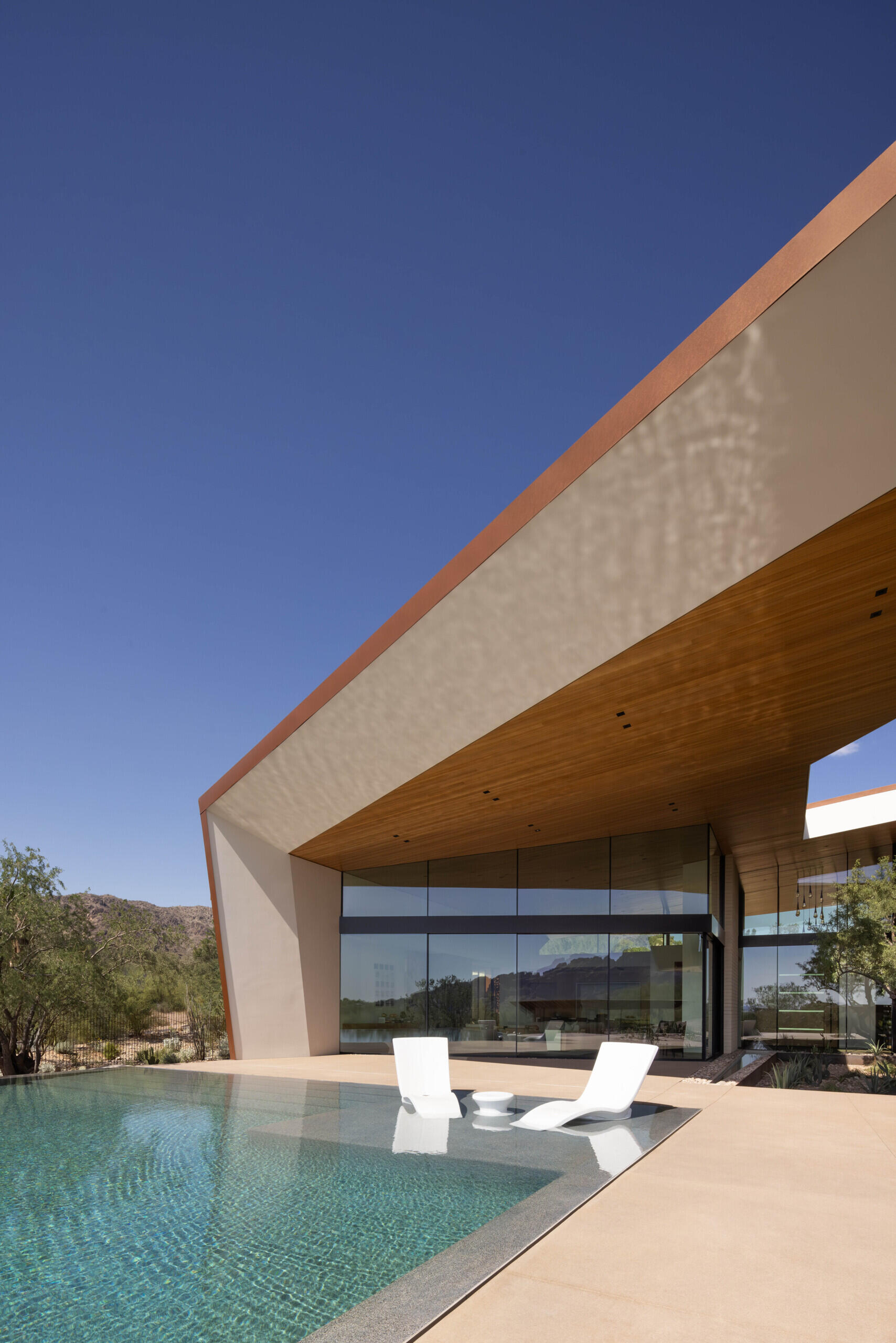 The infinity-edge pool cascades gently, its reflective surface mirroring the sky by day and glowing with sunset colors in the evening. This water feature also plays a role in passive cooling, enhancing comfort in the desert heat.