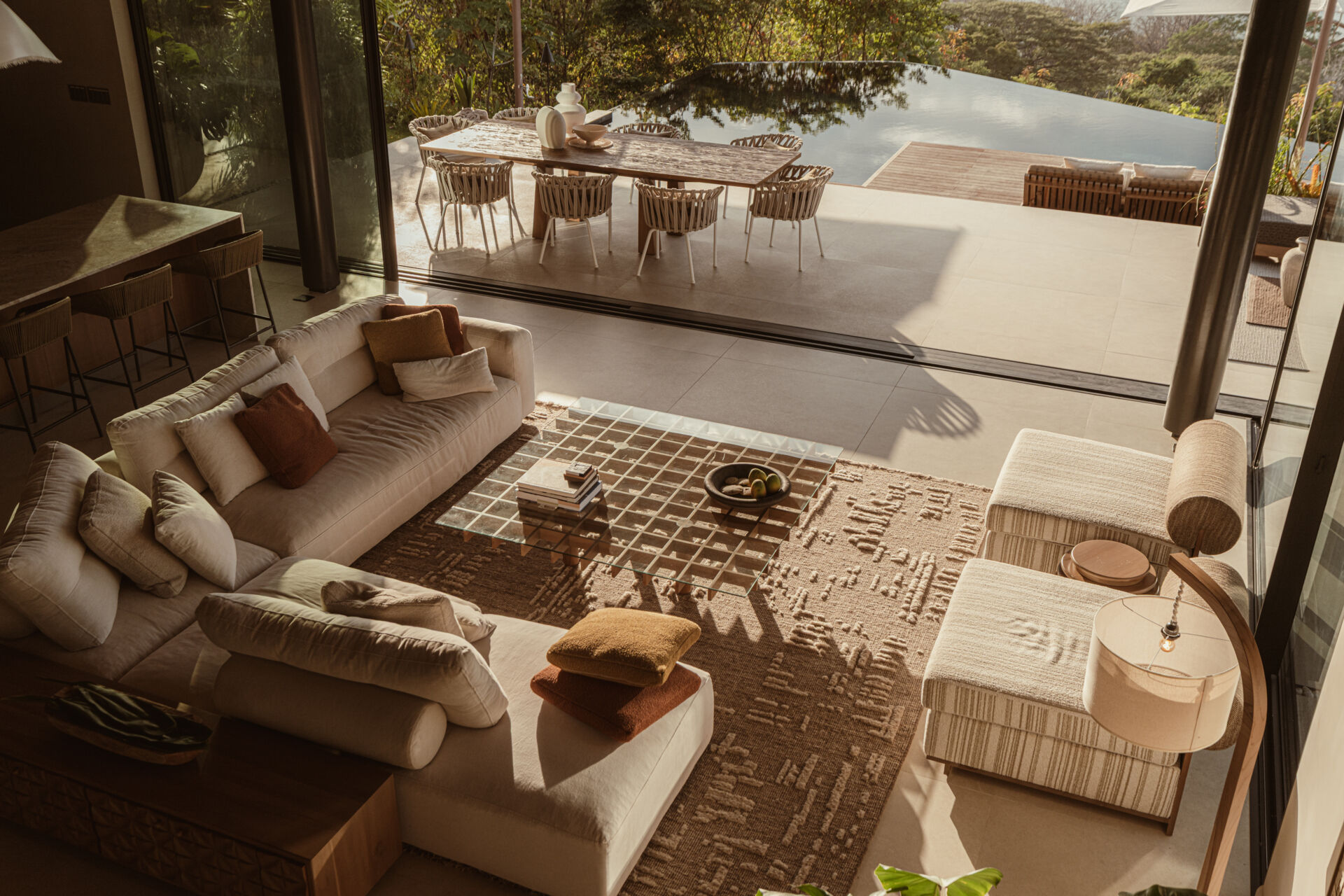 Natural stone, reforested teak, and custom-designed furniture define this breezy, open-plan living room and kitchen, that blurs the lines between indoors and out.