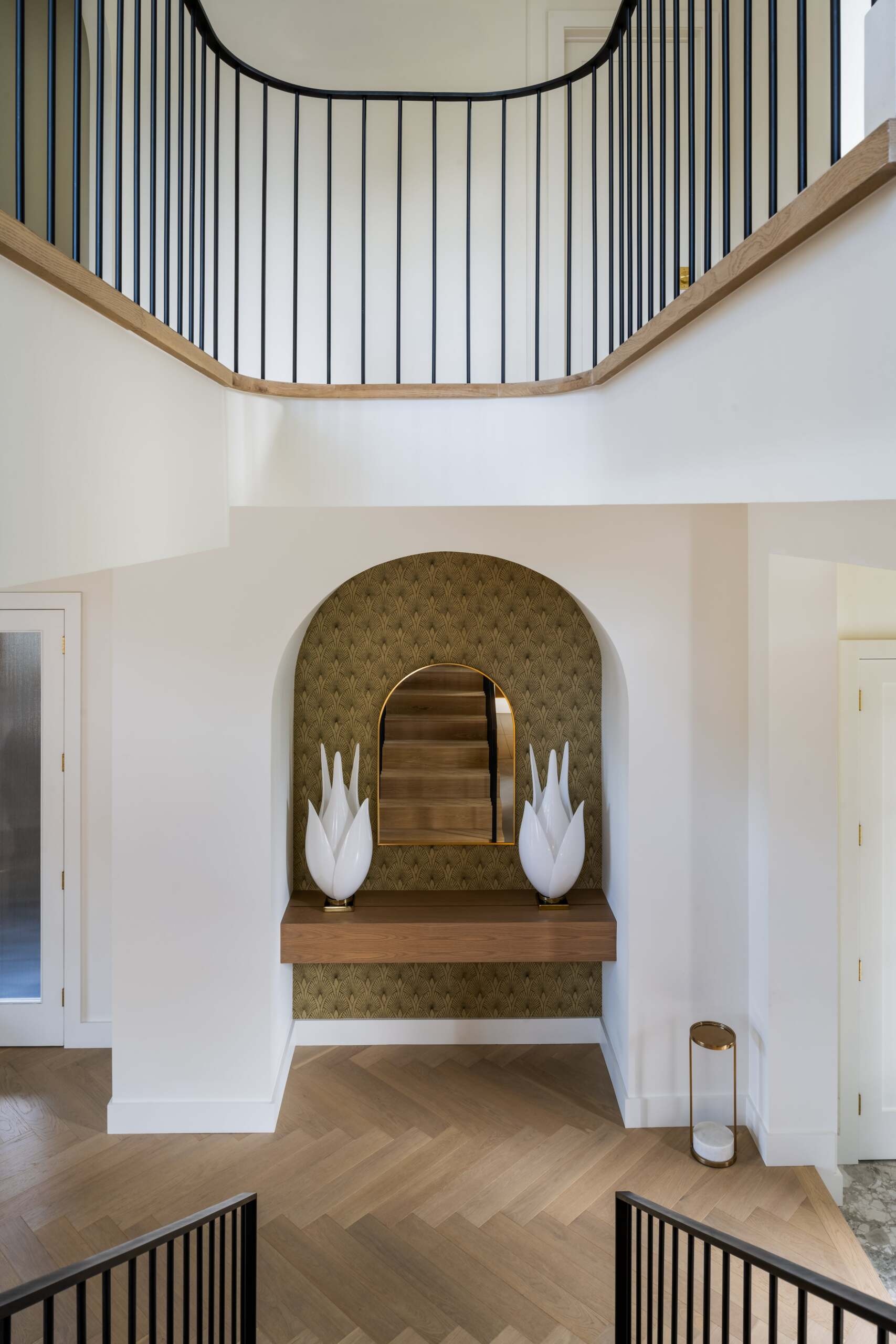 This staircase breaks from convention by not stacking directly between levels. Instead, its discreet placement allows for a more flexible layout. The semi-circular floor opening above gives it presence without overwhelming the interiors.