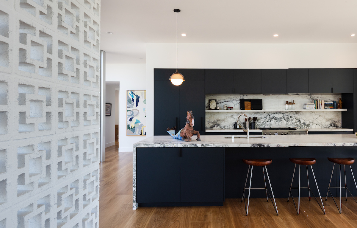 The kitchen carries the home’s modern aesthetic with matte black cabinetry, a spacious island, and crisp lines that echo the architecture.