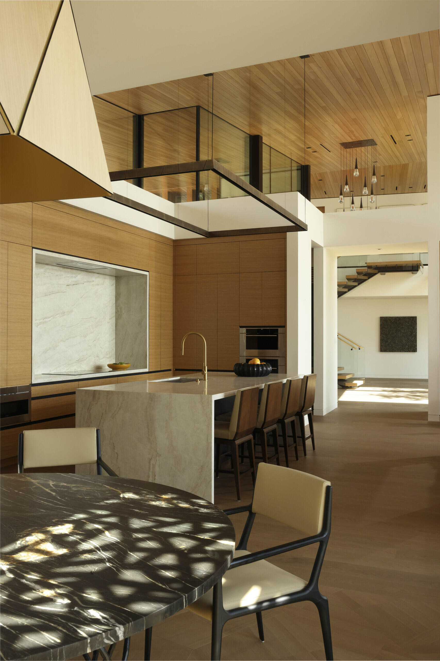 This kitchen continues the home’s natural material palette, combining warm wood tones with refined stone surfaces. Positioned near the open living spaces, it serves as both a functional hub and a visual extension of the design’s elegance.