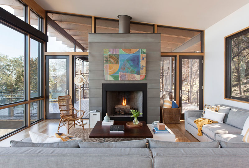A light filled living room with floor to ceiling windows and a fireplace, overlooking the lake near Marble Falls.