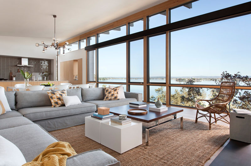 A light filled living room with floor to ceiling windows and a fireplace, overlooking the lake near Marble Falls.