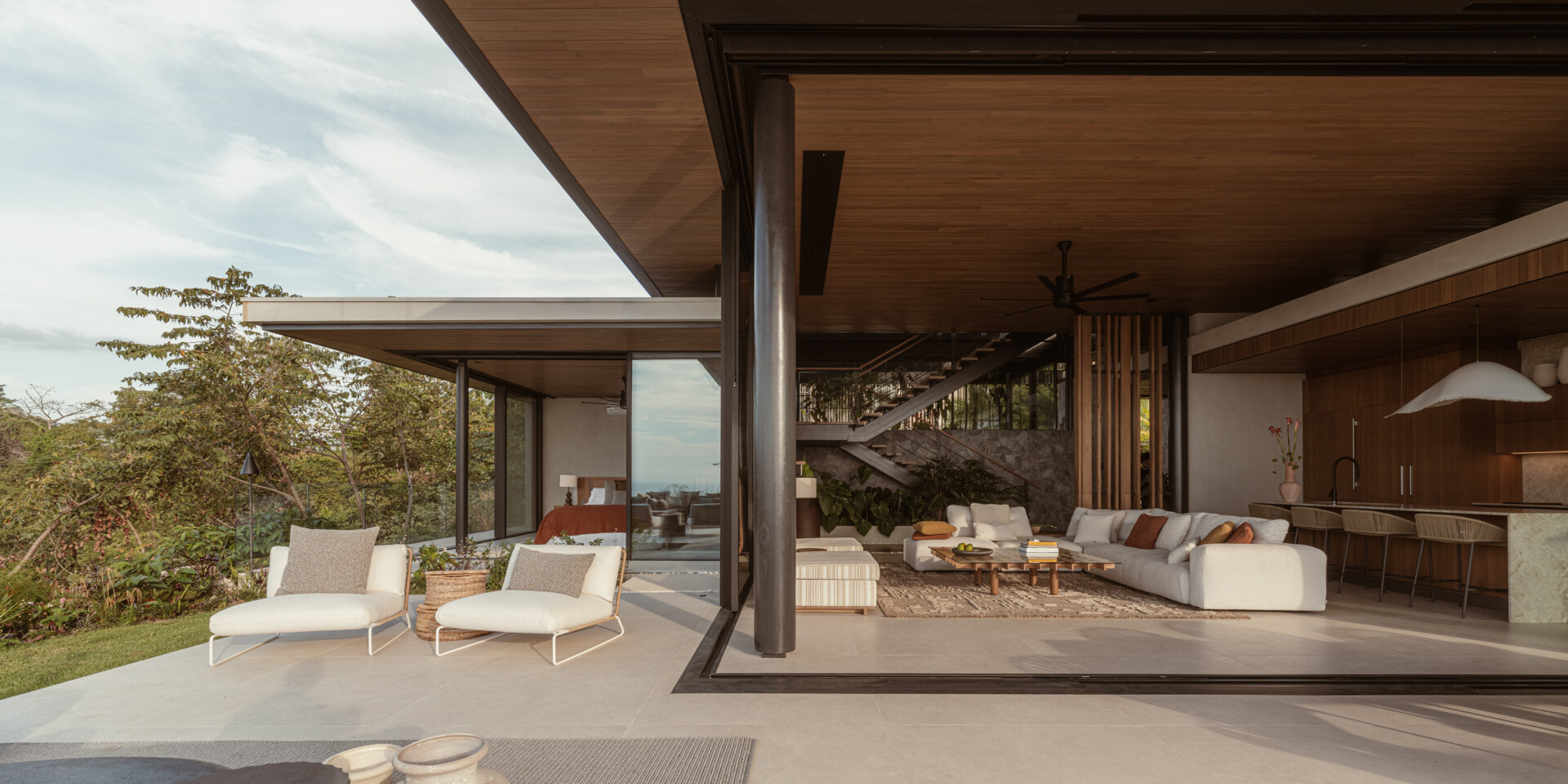 Natural stone, reforested teak, and custom-designed furniture define this breezy, open-plan living room and kitchen, that blurs the lines between indoors and out.