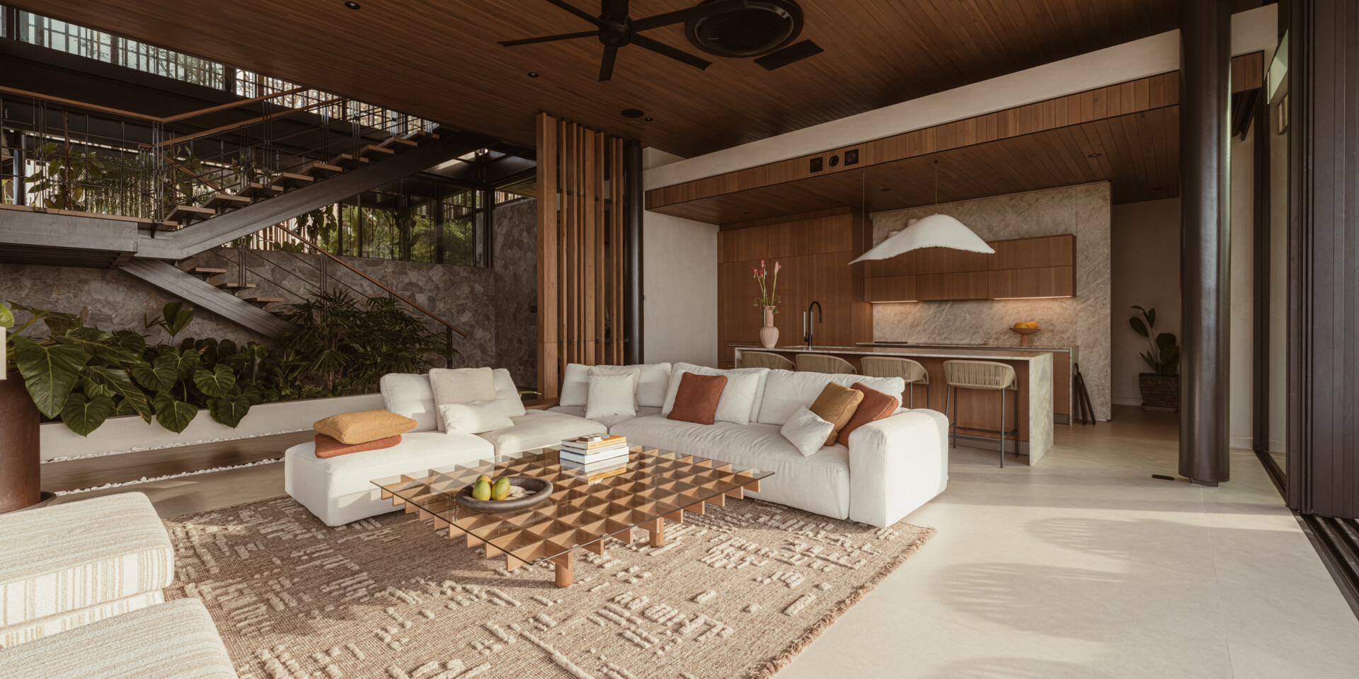 Natural stone, reforested teak, and custom-designed furniture define this breezy, open-plan living room and kitchen, that blurs the lines between indoors and out.