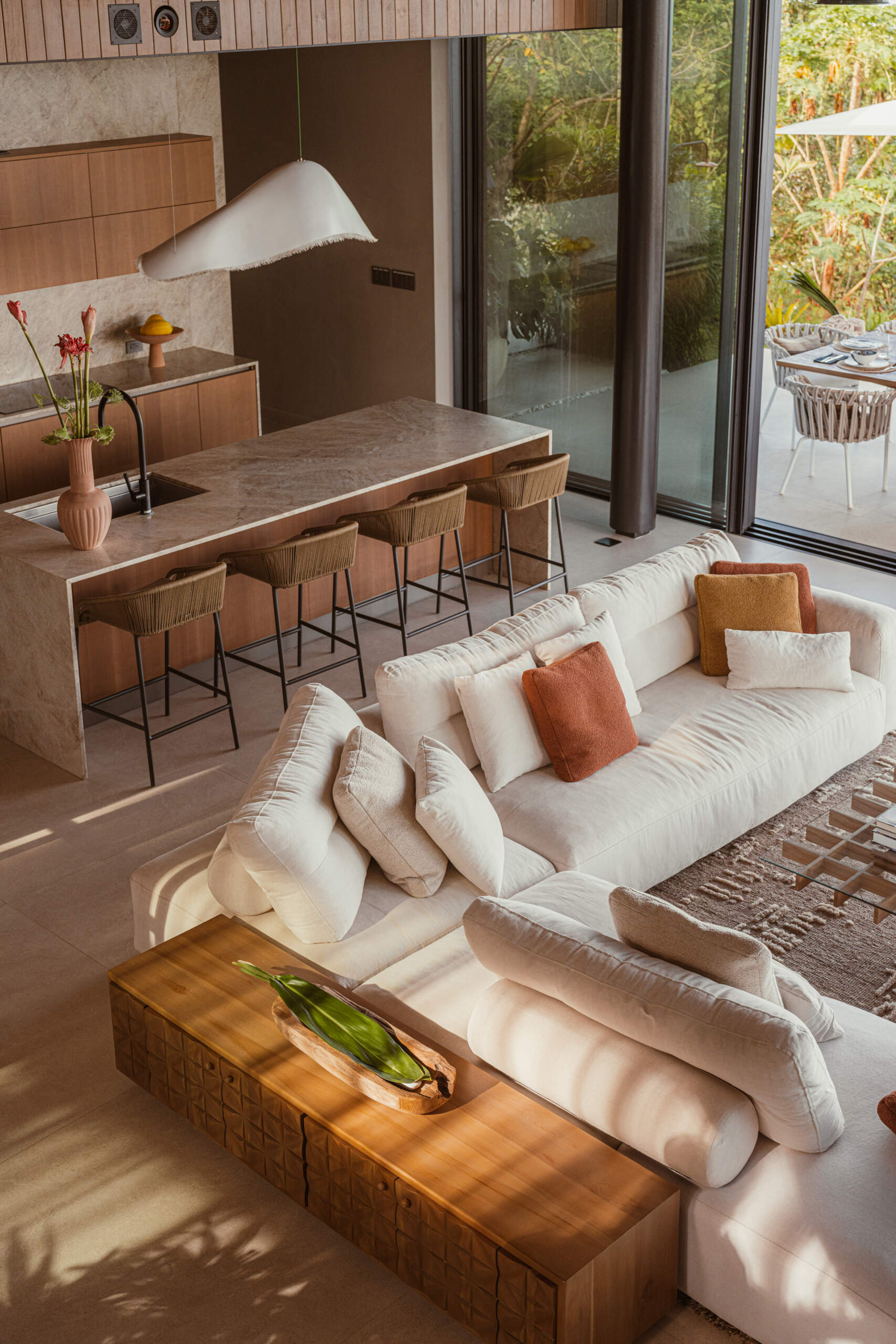 Natural stone, reforested teak, and custom-designed furniture define this breezy, open-plan living room and kitchen, that blurs the lines between indoors and out.