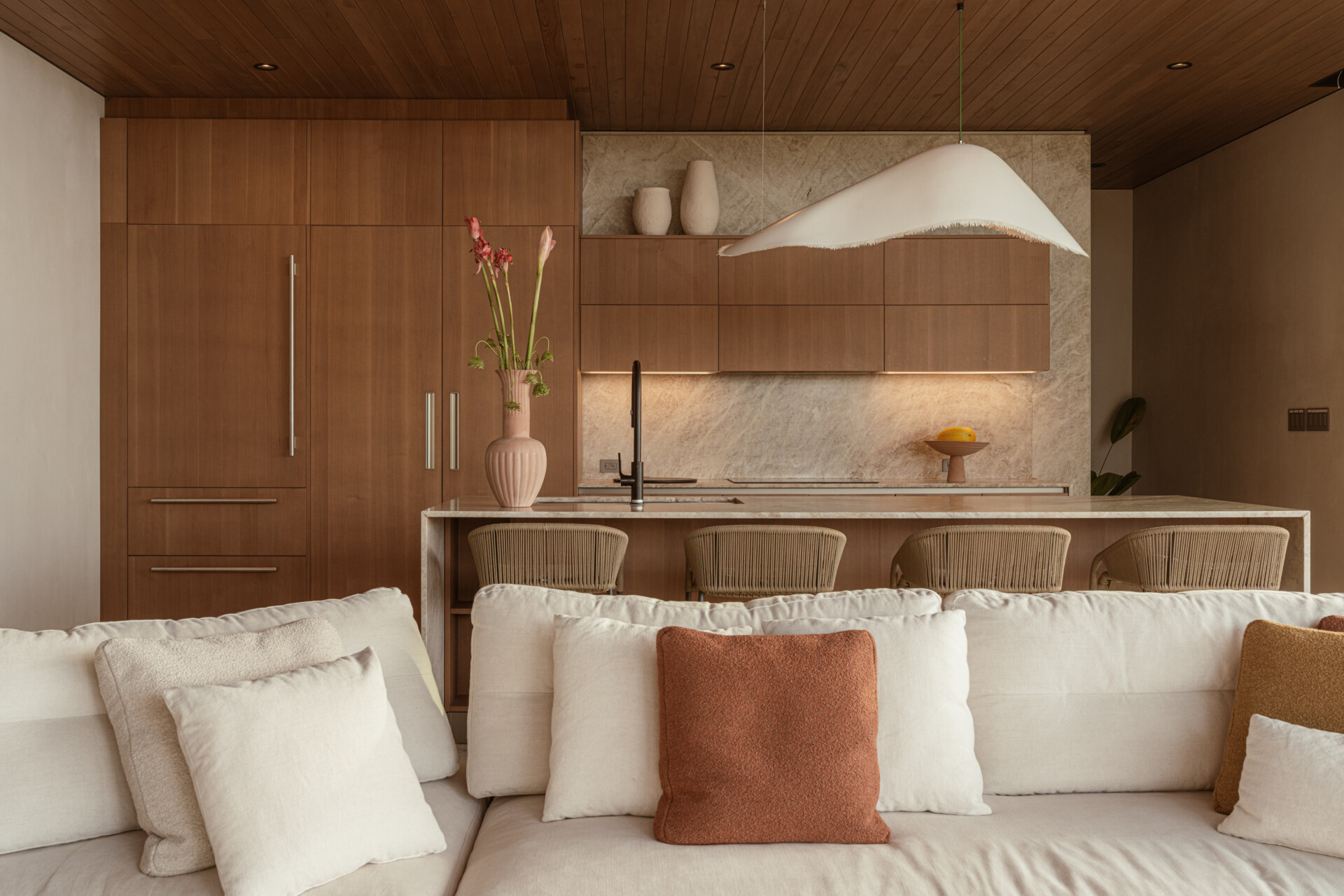 Natural stone, reforested teak, and custom-designed furniture define this breezy, open-plan living room and kitchen, that blurs the lines between indoors and out.