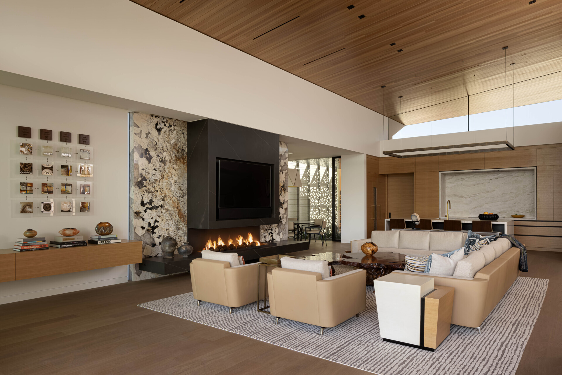 The great room is positioned to capture distant views of Camelback Mountain. Expansive glass under the sweeping roofline floods the space with daylight, while warm wood and stone finishes create an inviting atmosphere for gatherings.