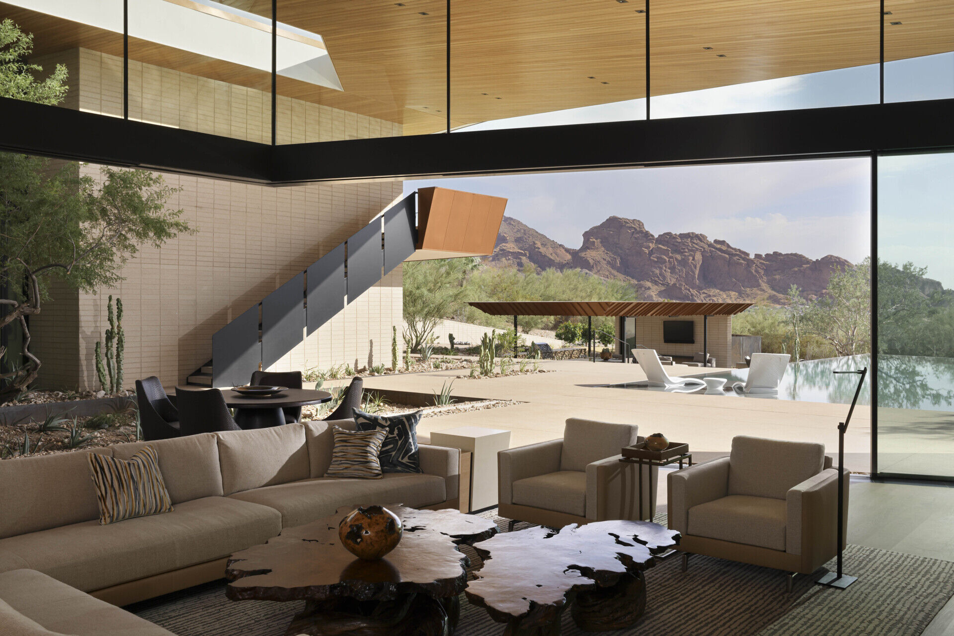 The great room is positioned to capture distant views of Camelback Mountain. Expansive glass under the sweeping roofline floods the space with daylight, while warm wood and stone finishes create an inviting atmosphere for gatherings.