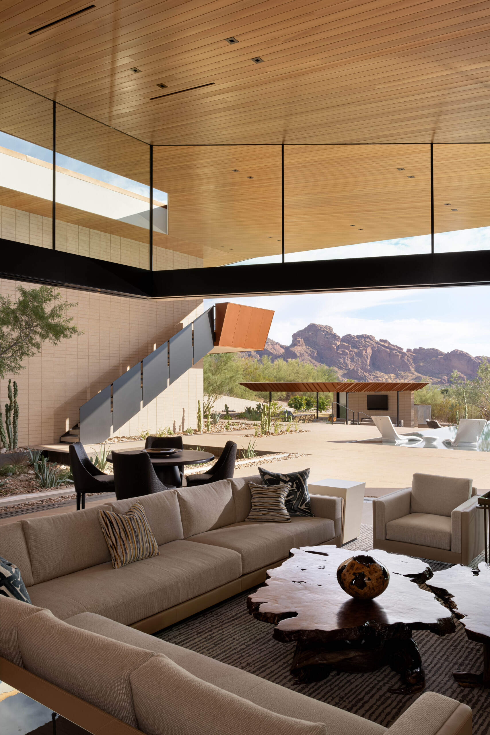 The great room is positioned to capture distant views of Camelback Mountain. Expansive glass under the sweeping roofline floods the space with daylight, while warm wood and stone finishes create an inviting atmosphere for gatherings.