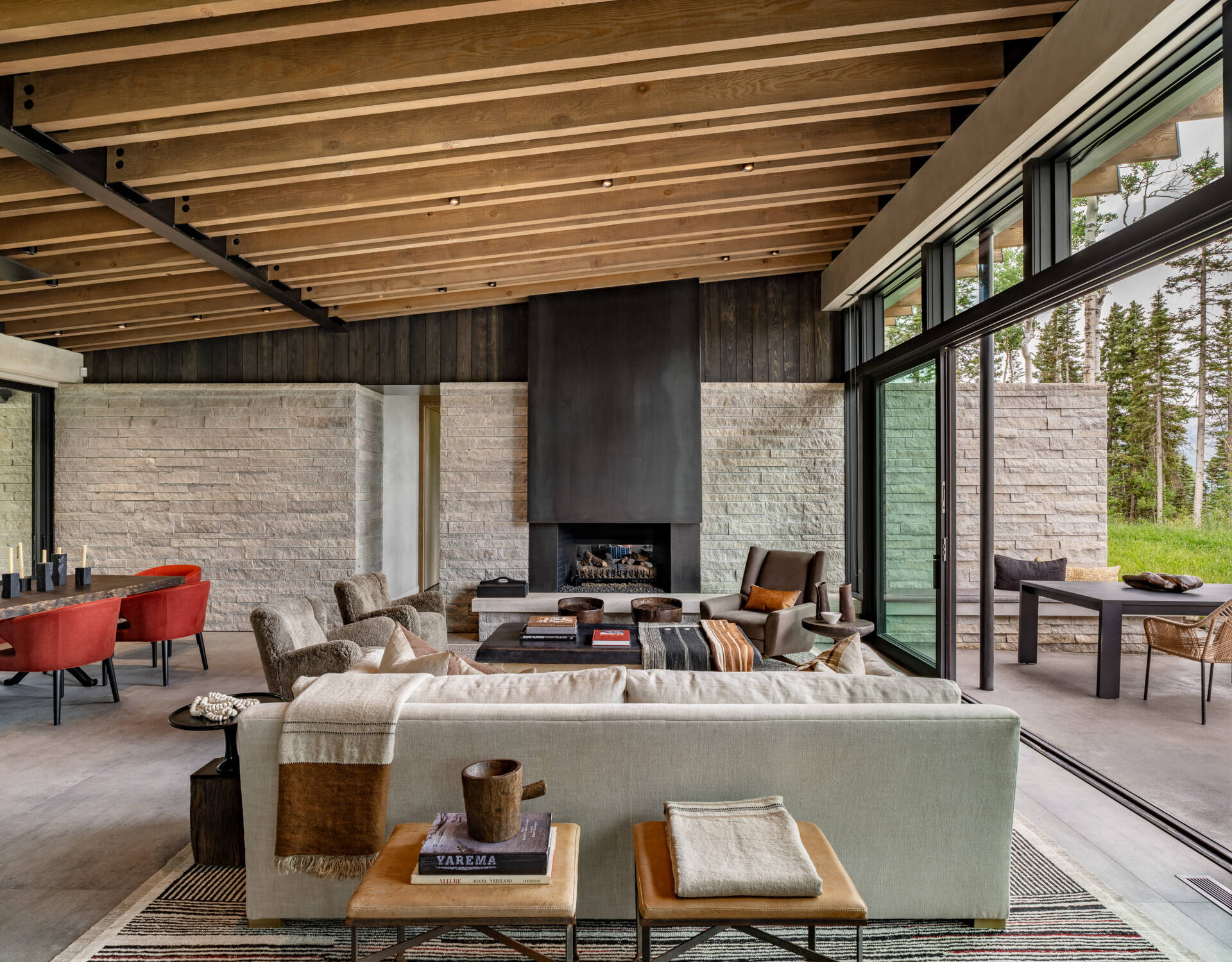 Exposed steel beams and wood rafters set the tone for this living space, balancing warmth and sophistication. A double-sided fireplace links the living room with the primary suite’s intimate reading den.