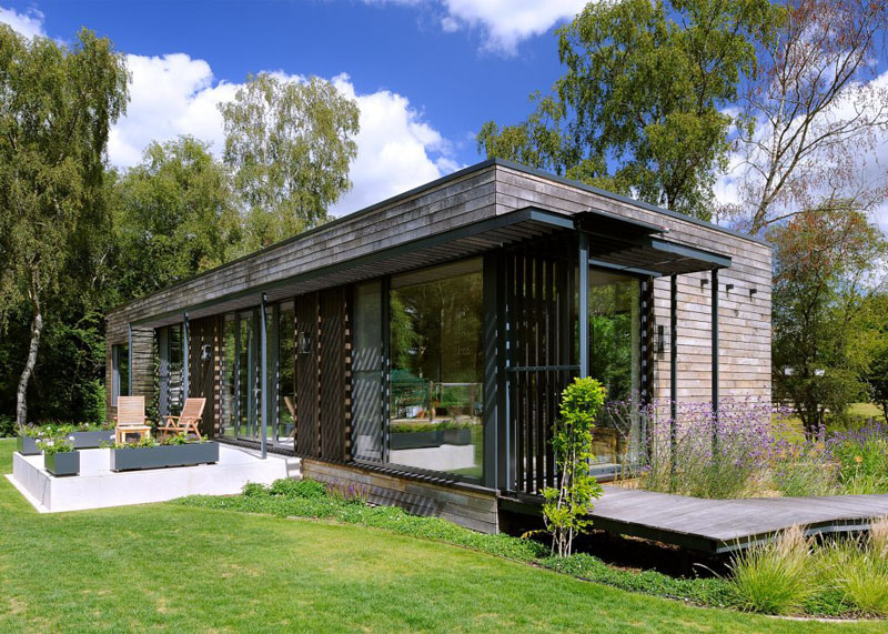 The exterior of this modern mobile home is wrapped in dark-stained sweet chestnut wood that gives it a sleek, grounded appearance.