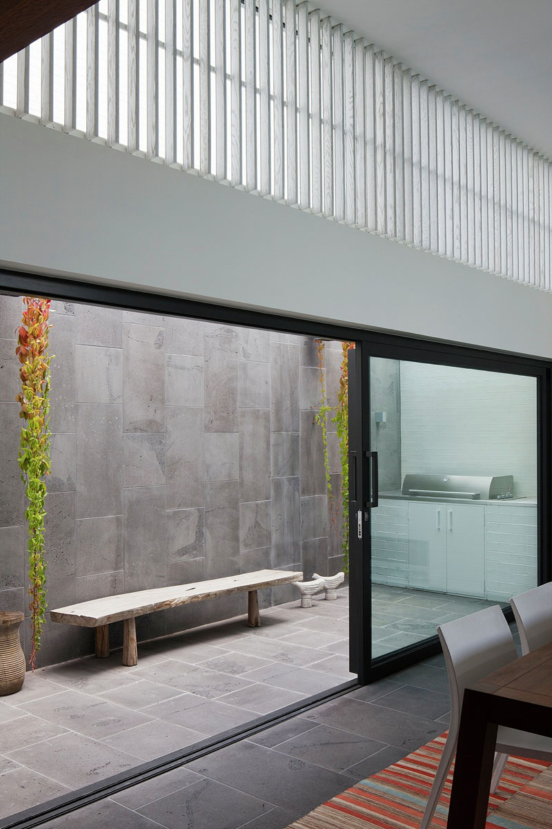 A modern home with a dining space anchored by a colorful rug, leading to a private patio with a BBQ area.