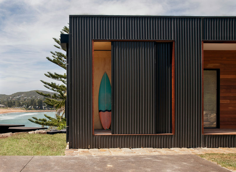 A modern 2 bedroom prefab home with a green roof, wraparound deck, and surfboard storage.
