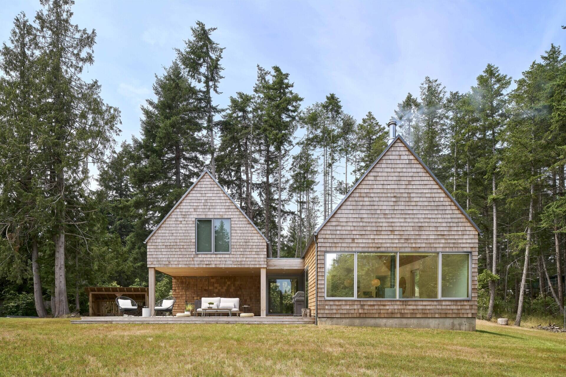 The exterior of this modern cabin is clad in natural cedar shingles, giving the modern form a timeless texture that resonates with the forest surroundings.