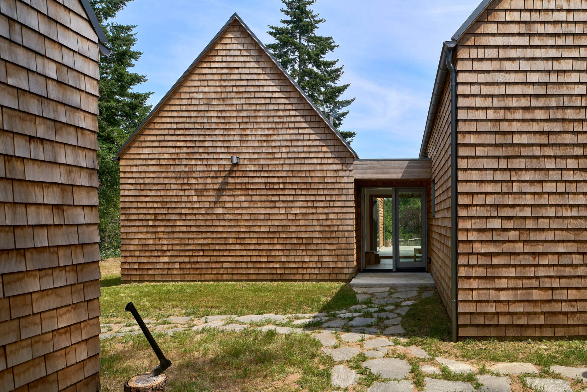 The exterior of this modern cabin is clad in natural cedar shingles, giving the modern form a timeless texture that resonates with the forest surroundings.