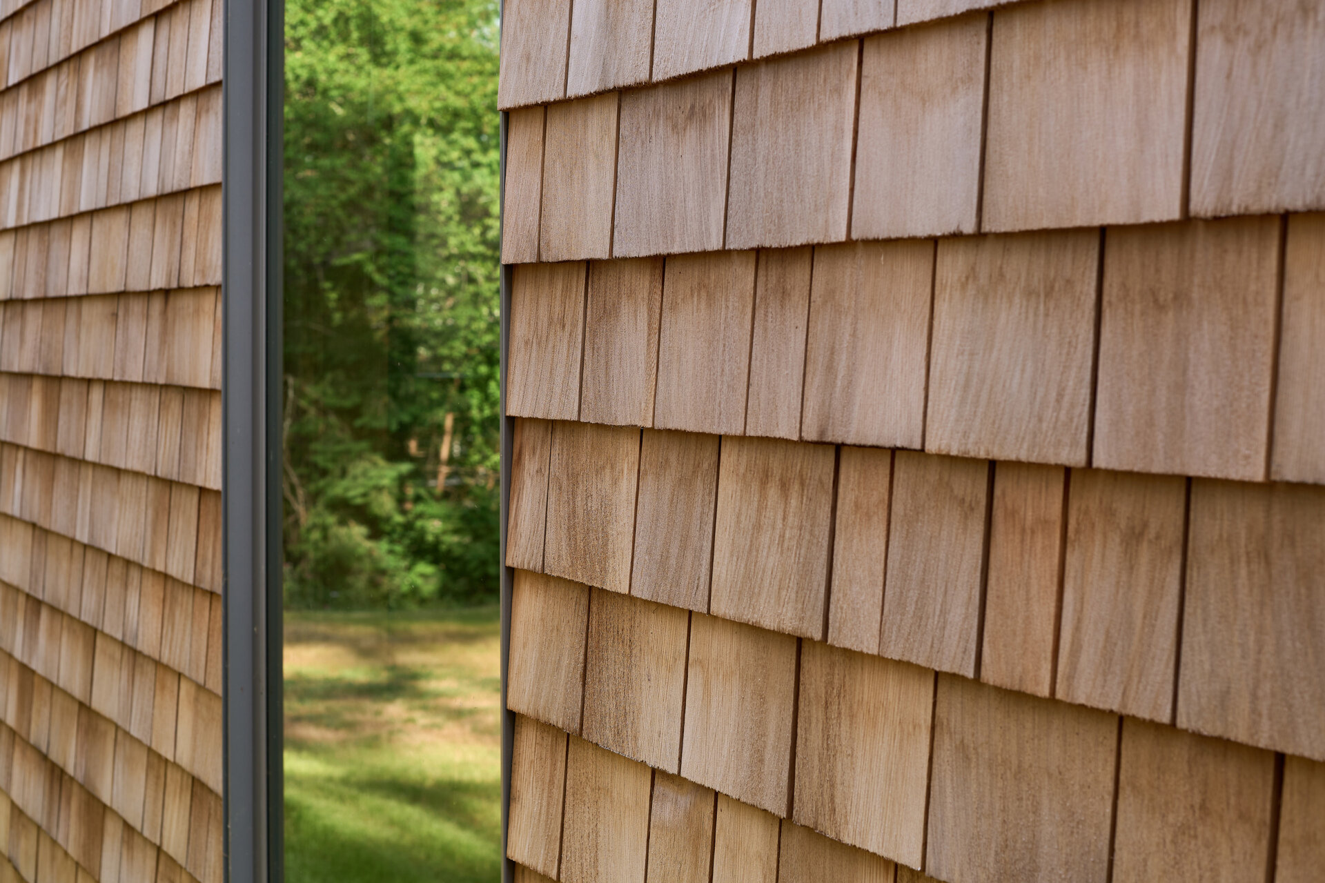 The exterior of this modern cabin is clad in natural cedar shingles, giving the modern form a timeless texture that resonates with the forest surroundings.