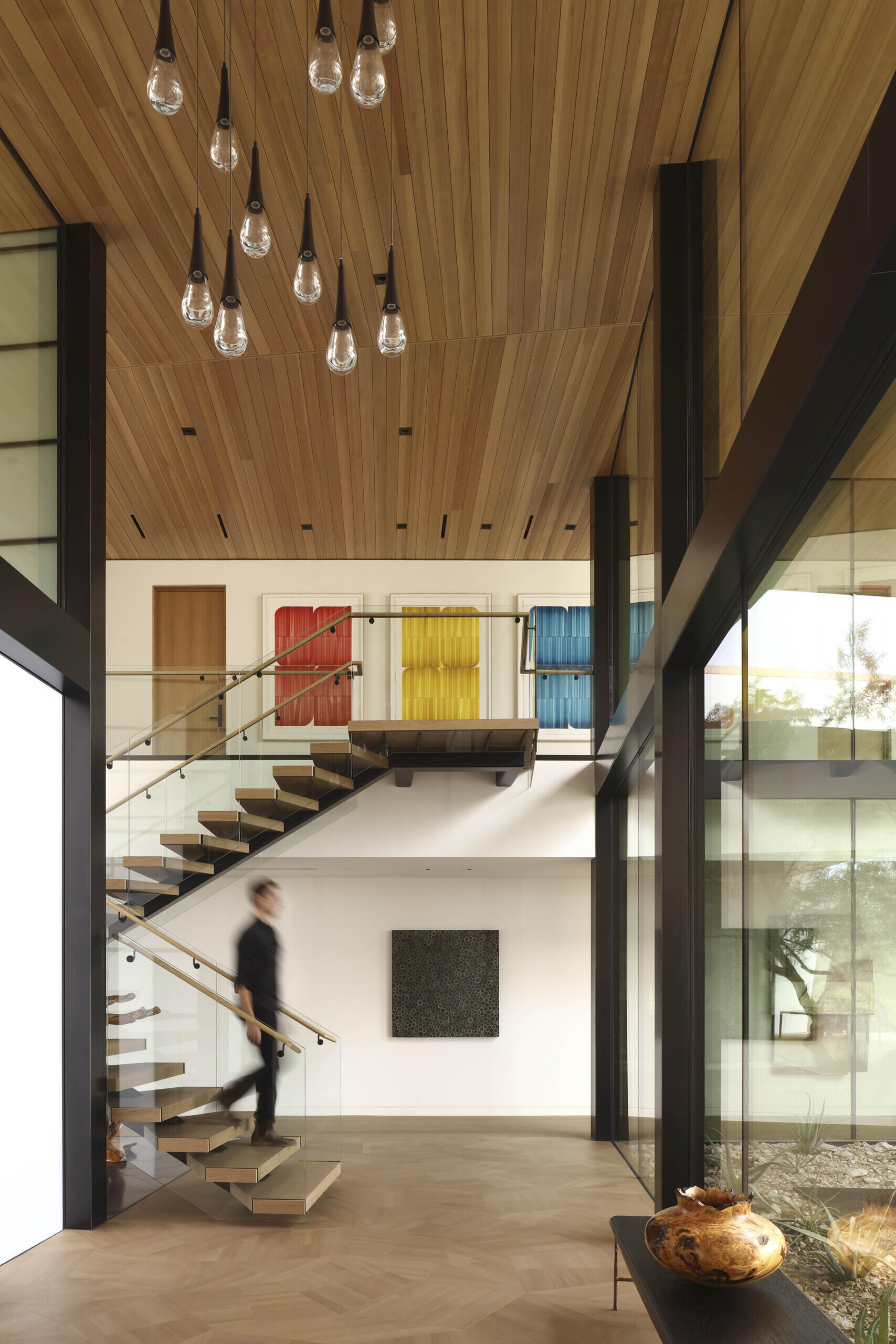 A floating staircase with angular wooden treads mirrors the home’s sharp architectural lines. This sculptural element connects levels while casting shadows that shift with the desert light.