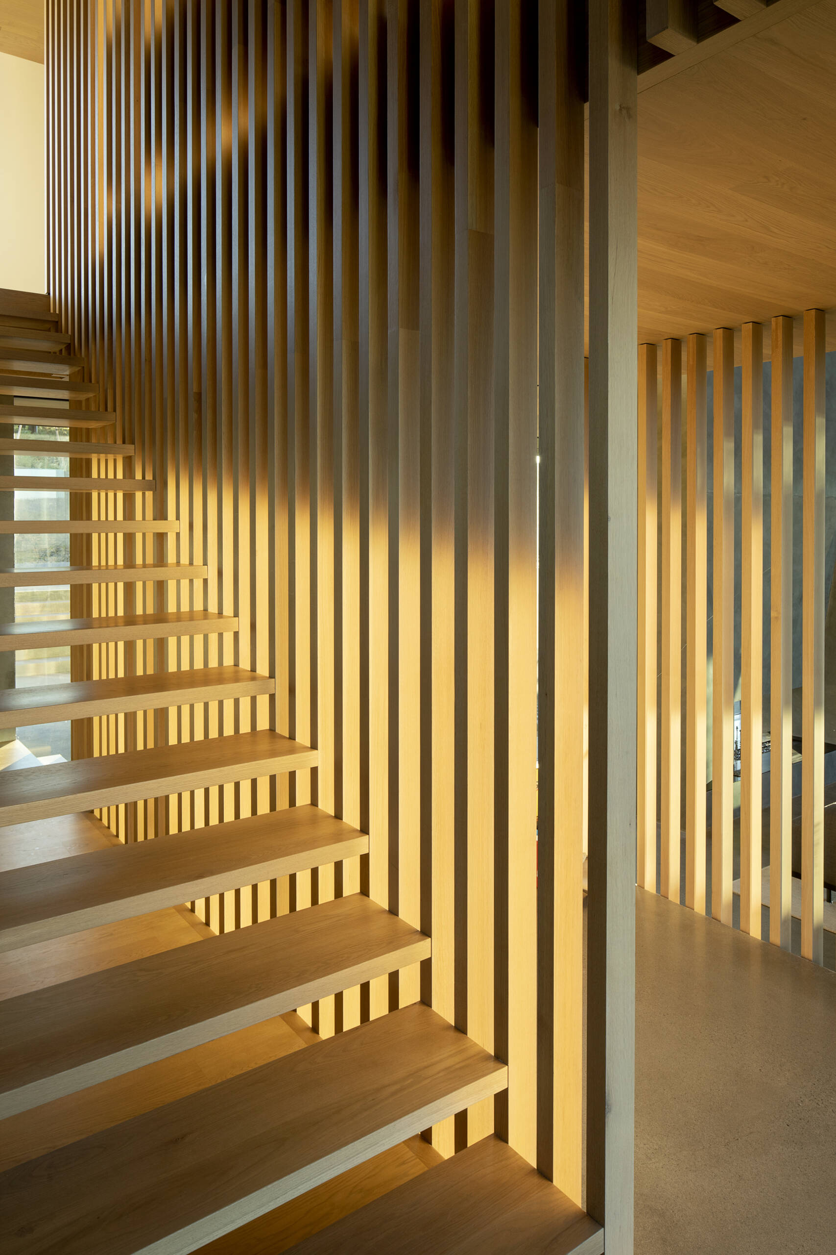 Movement through the home is choreographed by a distinct staircase, supported by a finely crafted wood screen, connecting to the upper level and adding a layer of spatial separation. 