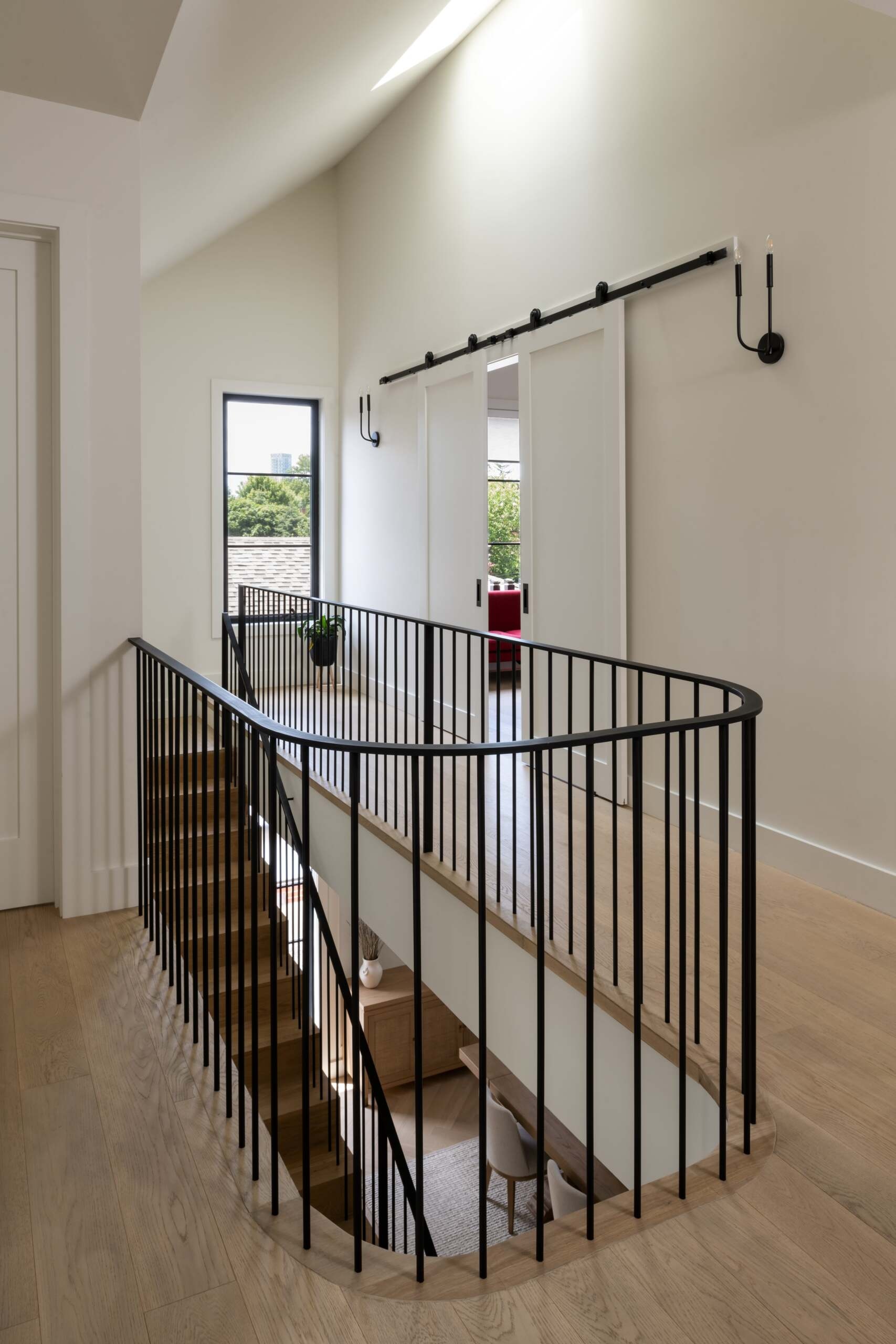 This staircase breaks from convention by not stacking directly between levels. Instead, its discreet placement allows for a more flexible layout. The semi-circular floor opening above gives it presence without overwhelming the interiors.