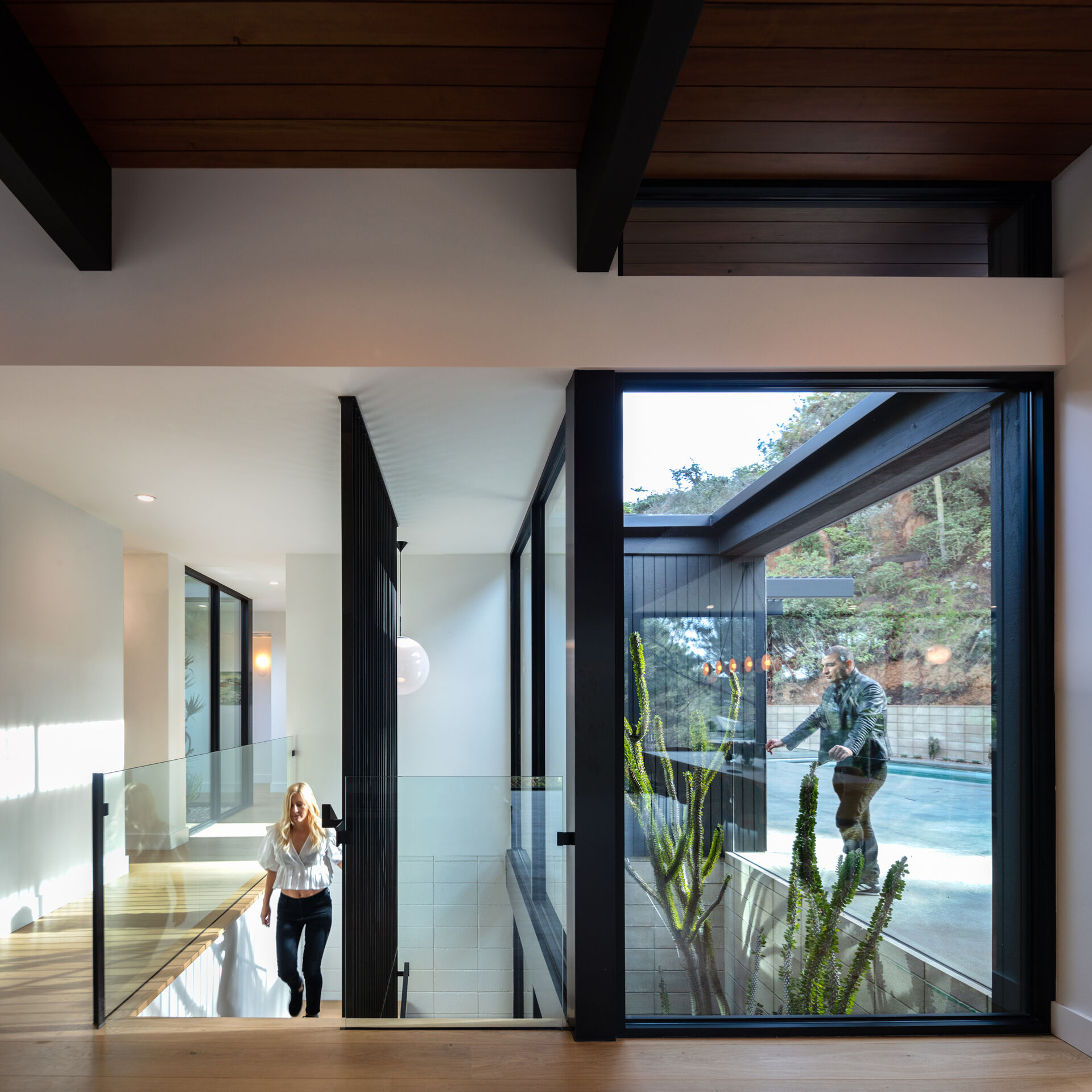 Modern wood and steel stairs are next to an atrium with plants.