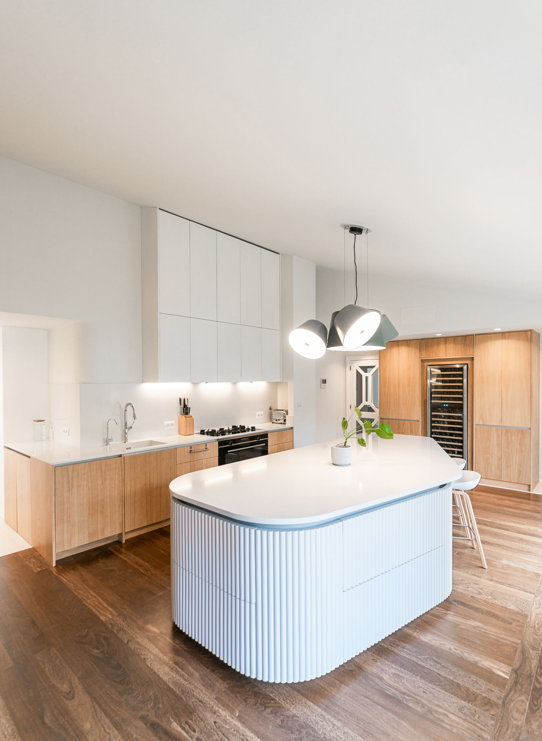 Minimalist wood cabinetry, a sculptural ribbed island, and soft curves define this contemporary kitchen renovation. Natural textures and original timber floors bring warmth, while the curved forms add movement and balance to the clean, modern layout.