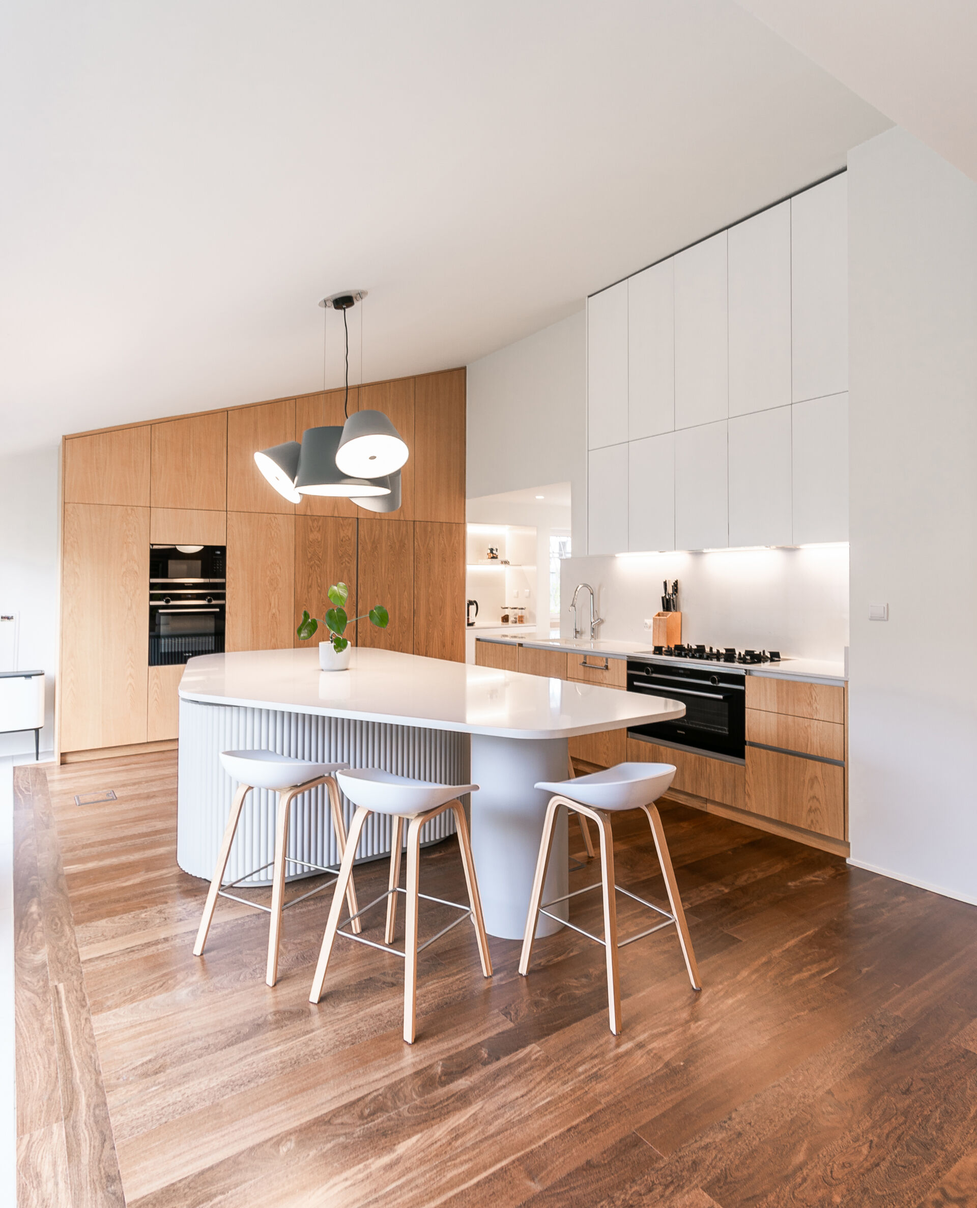 Minimalist wood cabinetry, a sculptural ribbed island, and soft curves define this contemporary kitchen renovation. Natural textures and original timber floors bring warmth, while the curved forms add movement and balance to the clean, modern layout.
