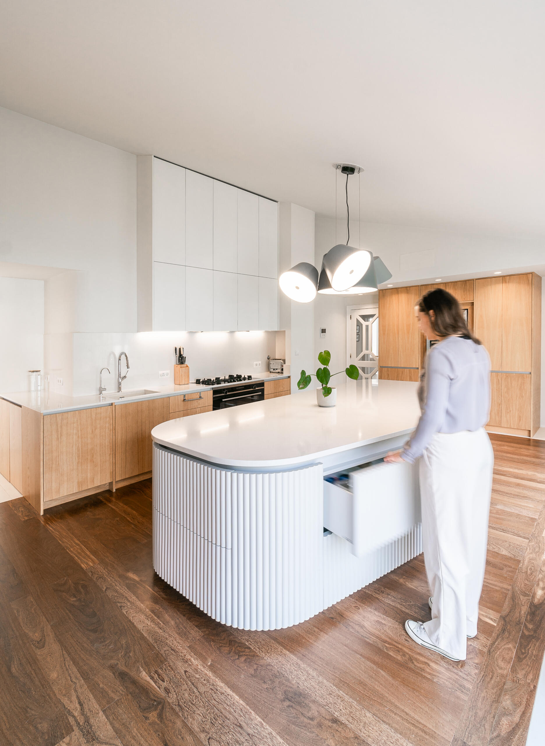 Minimalist wood cabinetry, a sculptural ribbed island, and soft curves define this contemporary kitchen renovation. Natural textures and original timber floors bring warmth, while the curved forms add movement and balance to the clean, modern layout.