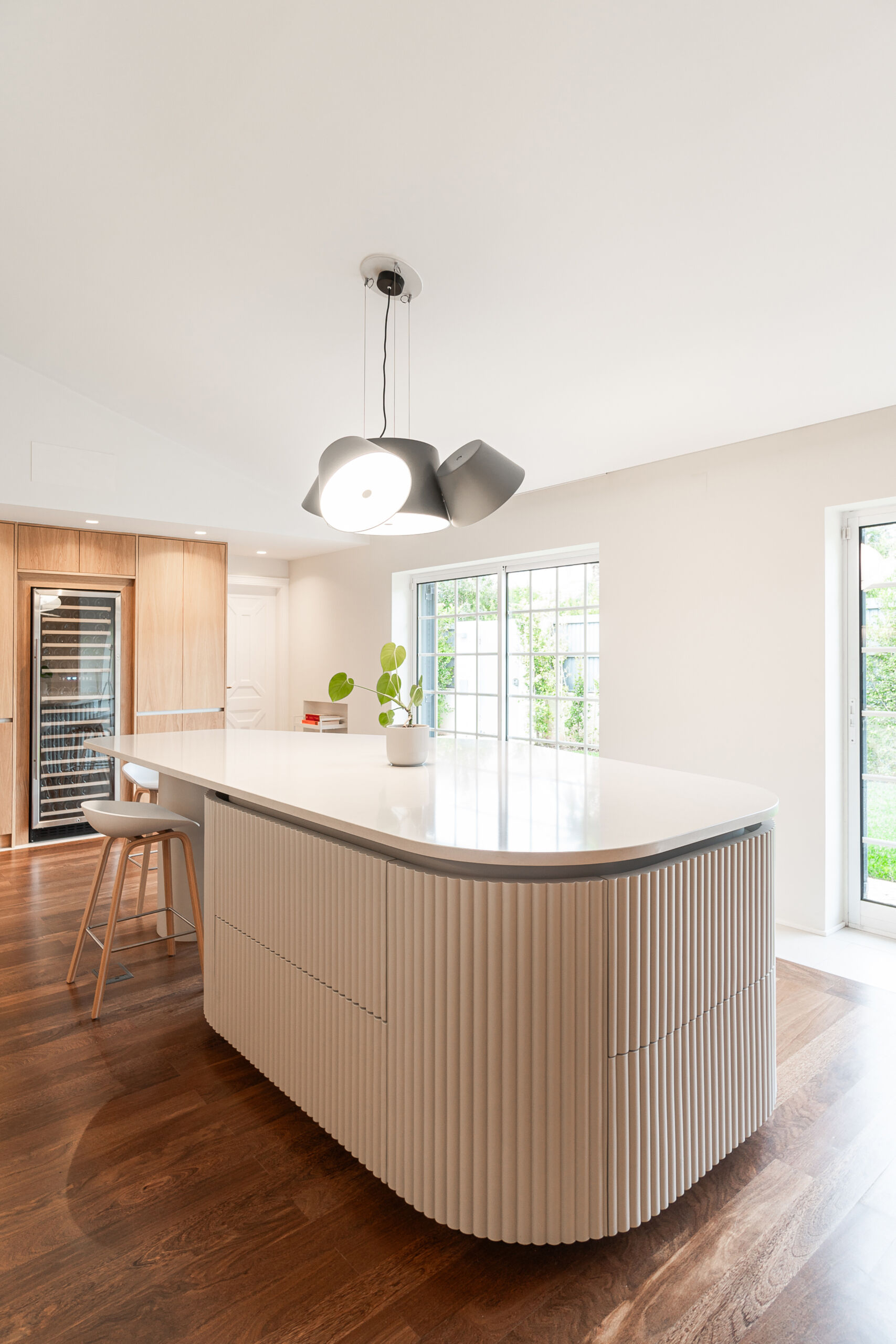 Minimalist wood cabinetry, a sculptural ribbed island, and soft curves define this contemporary kitchen renovation. Natural textures and original timber floors bring warmth, while the curved forms add movement and balance to the clean, modern layout.