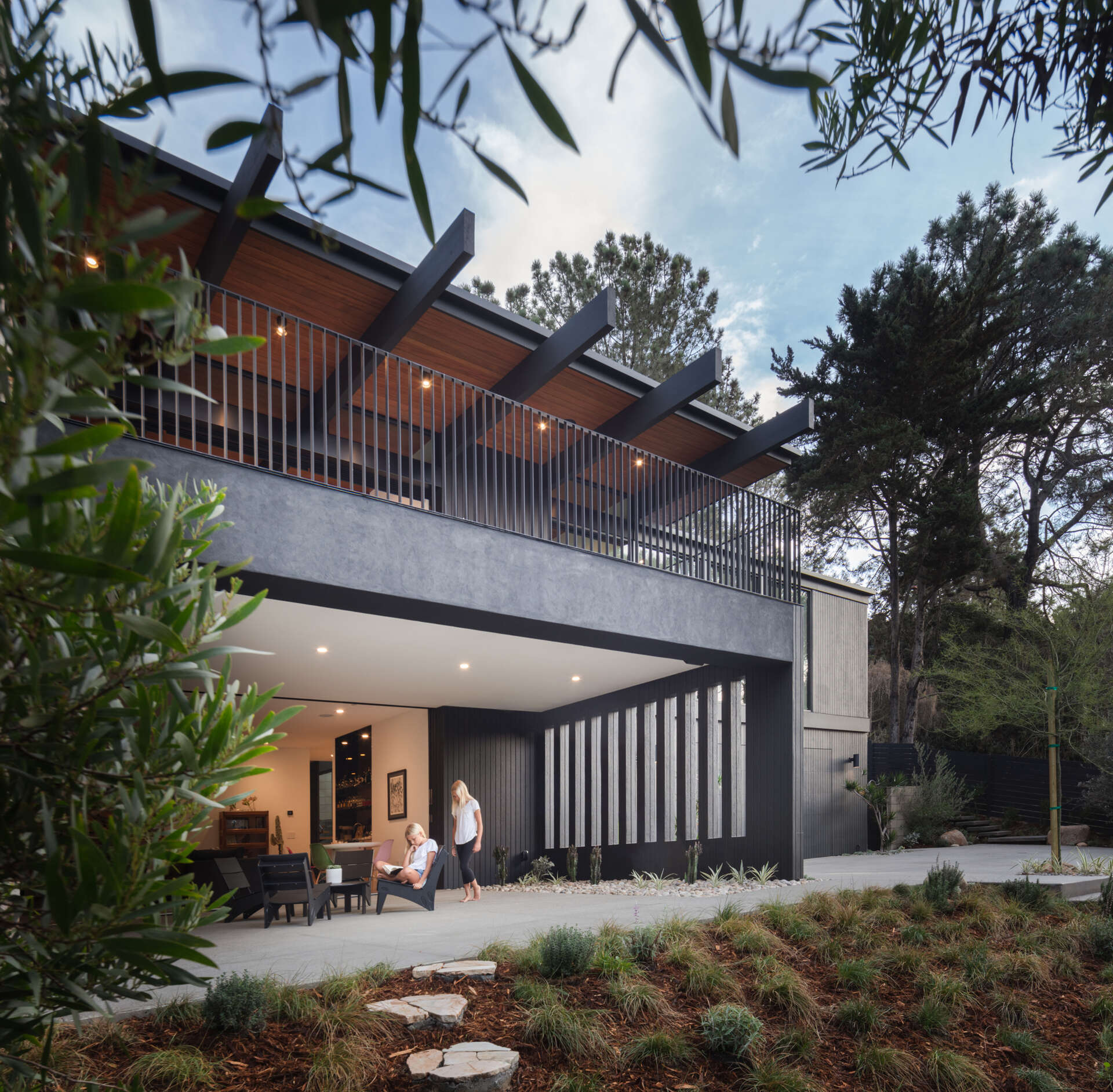 A mid-century modern inspired home with a glass, black, and stone exterior, and a bright oversized front door.