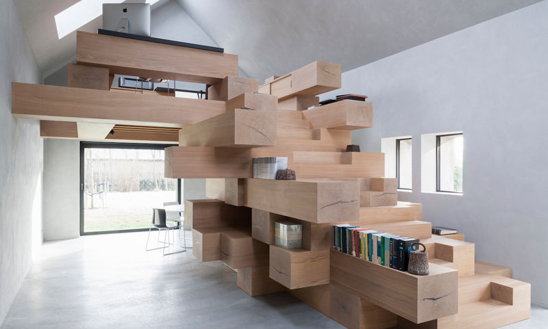 A small Belgian barn has been transformed into a sculptural, light-filled office with stacked wooden beams.