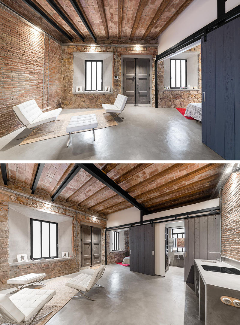 A guest suite in Barcelona that doubles as a studio, featuring exposed stone walls, a polished concrete floor, and flexible barn doors.