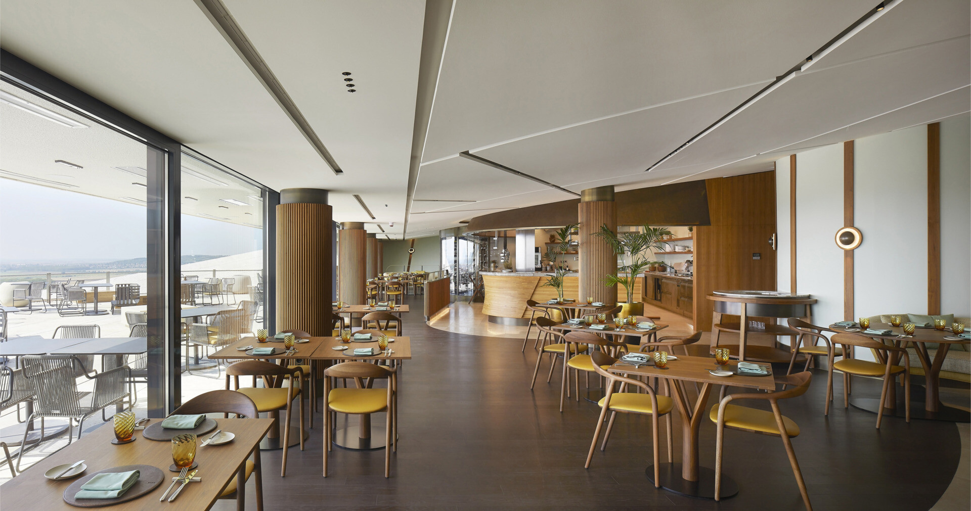 The curved glass entrance and skylit lobby guide visitors inward, framing vineyard views and creating a warm, welcoming transition from outdoors to interior.