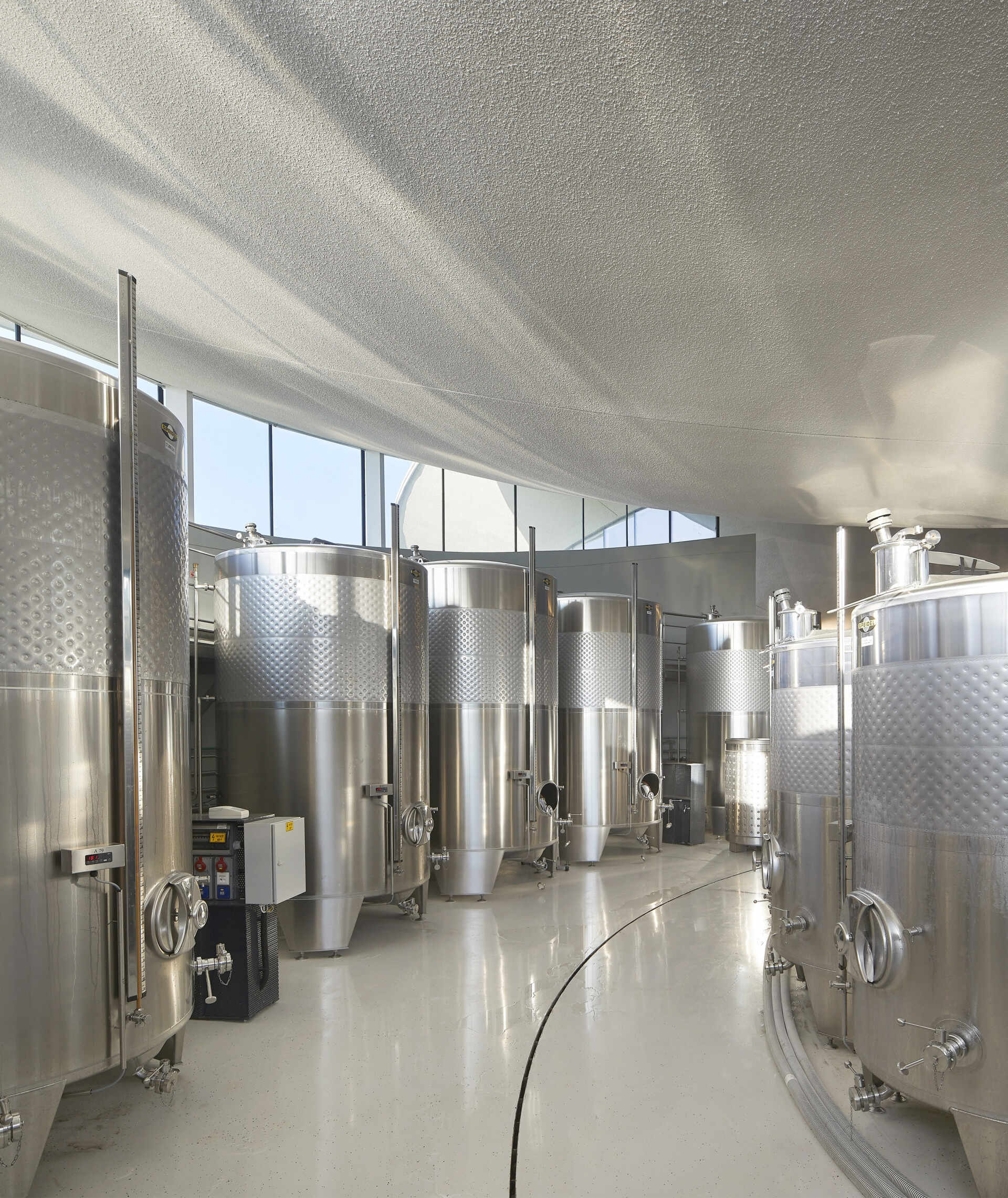 Underground fermentation, bottling, and storage areas ensure efficient winemaking, with a sleek, metallic aesthetic contrasting the warm, inviting visitor spaces above.